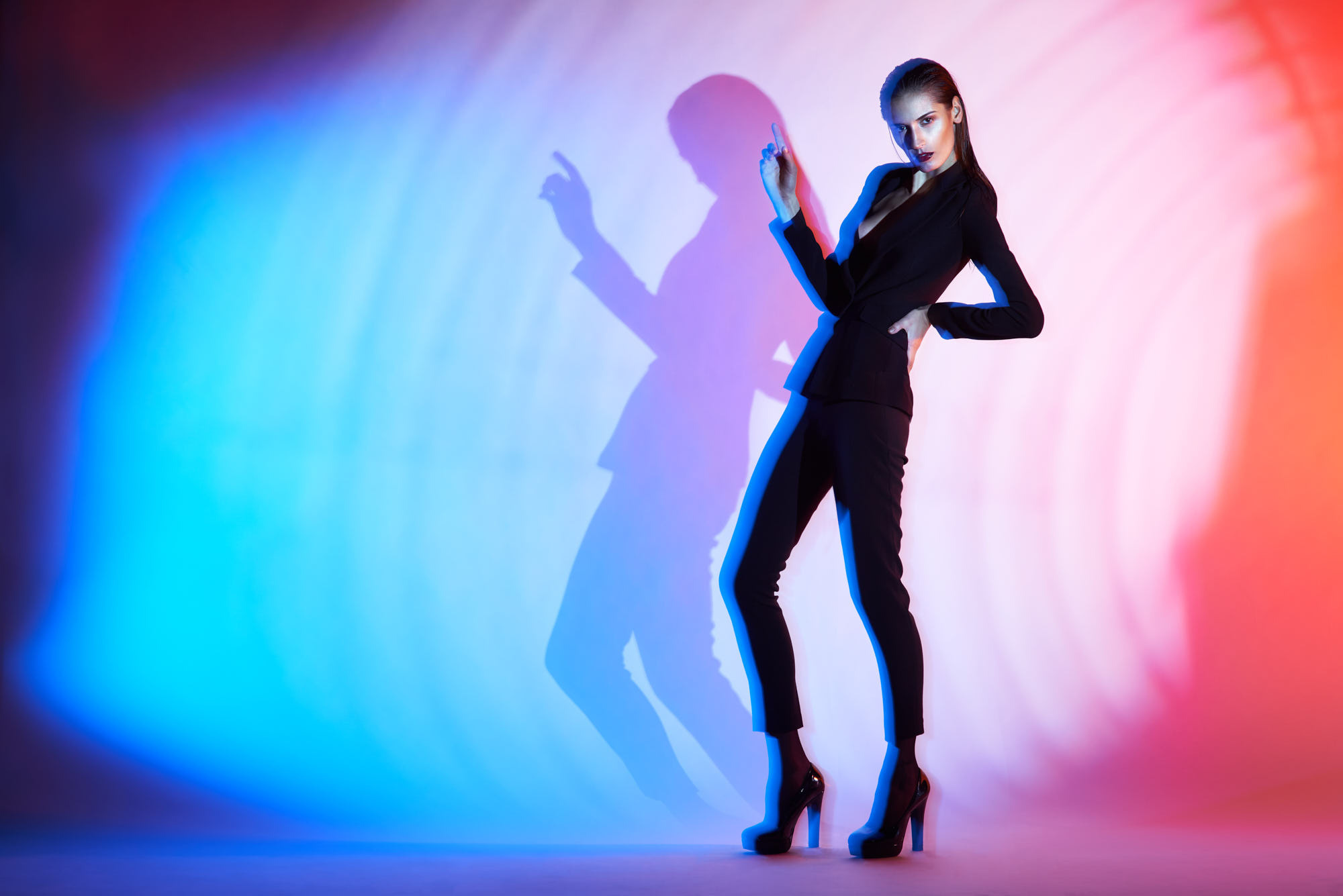Mixed light studio shot of skinny girl in black suit. Blue and red LED lights.