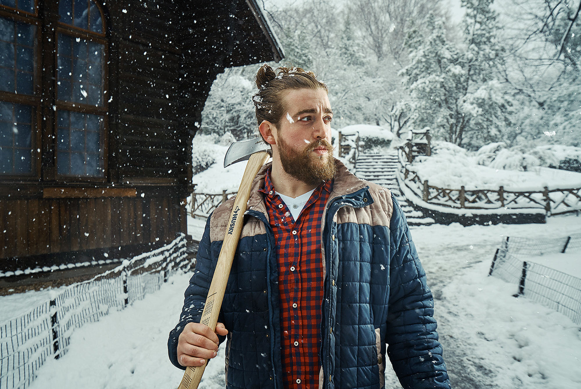 Lumberjack Alex Frankel in snow storm at Shakespeare garden, Central Park, New York with full lengh Husky Axe.