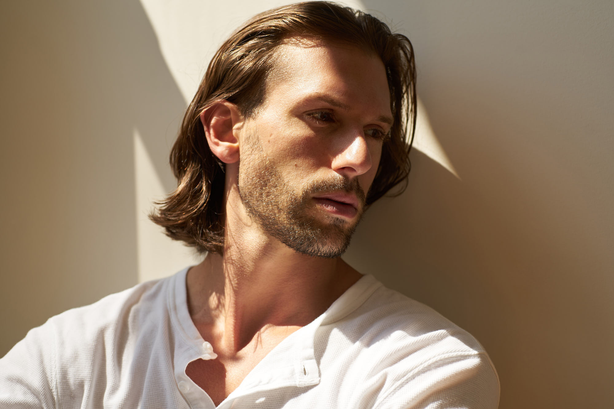 Handsome long haired men sitting behind the wall.