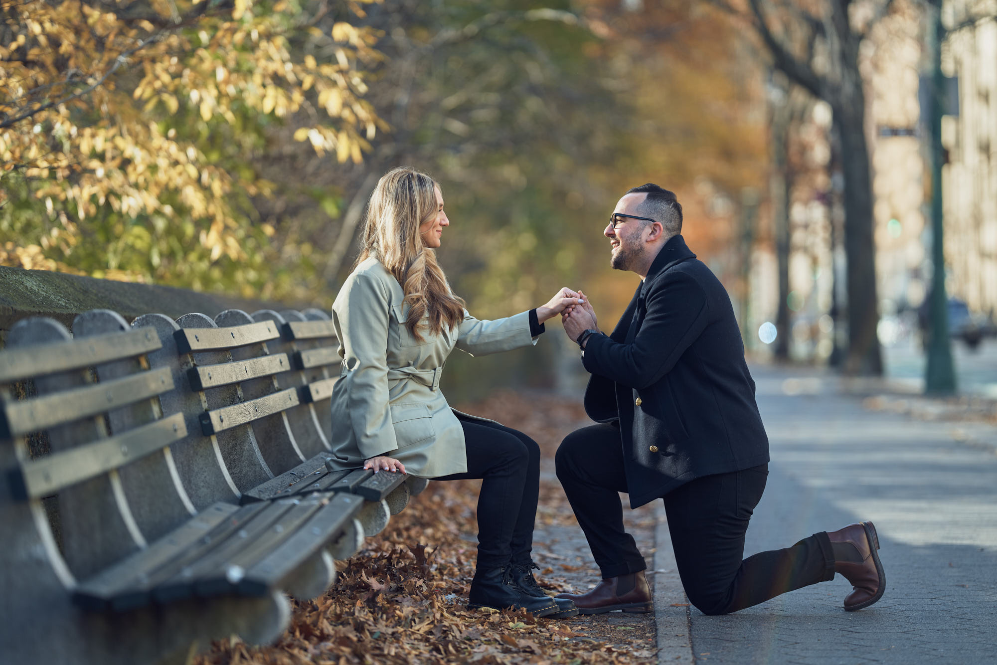 Fall engagement photoshoot in Central park captured by photographer Alex Pedan. Groom-to-be on one knee proposing to his partner.