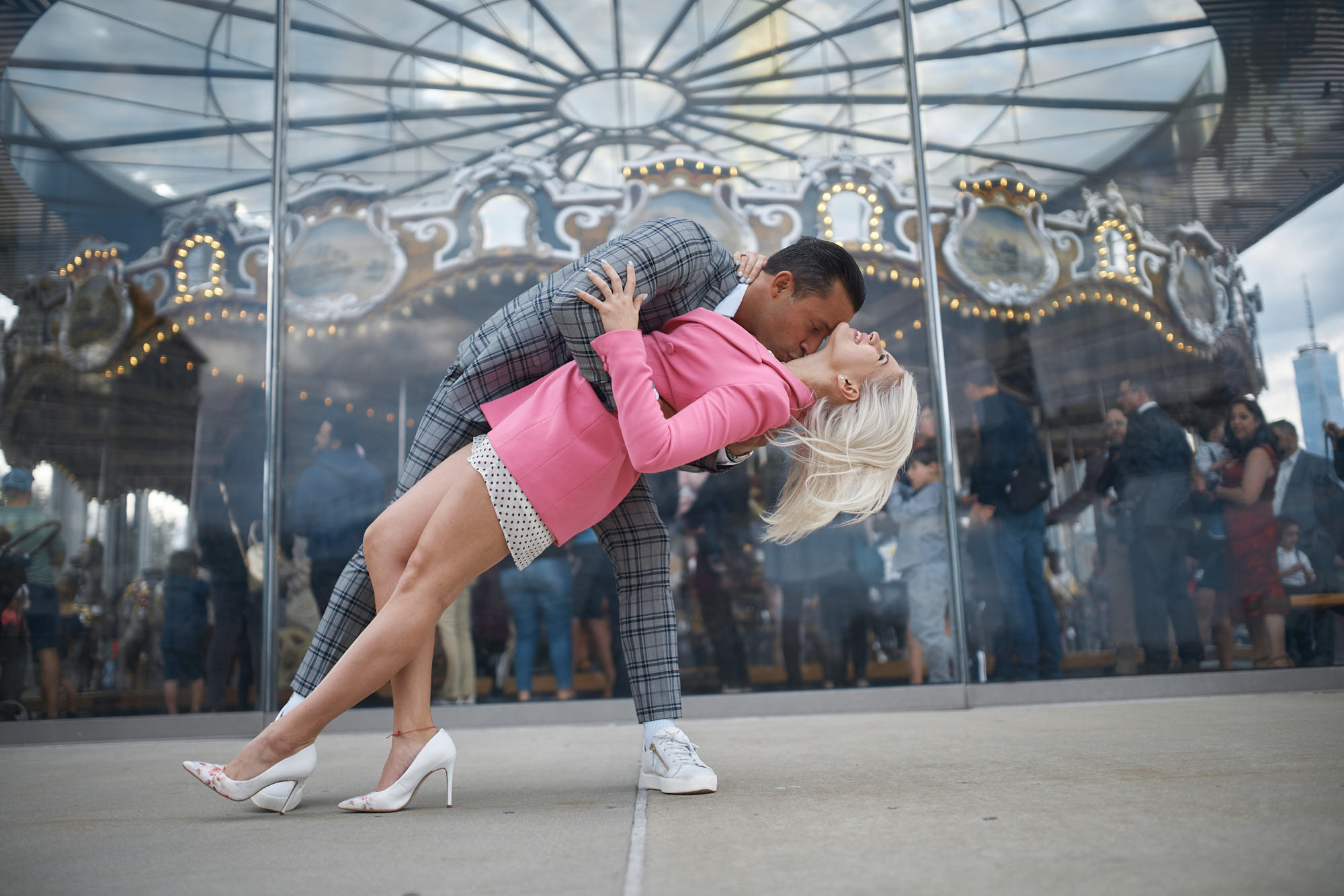 Couples photographer Alex Pedan captures romantic moment of groom supporting his fiance by her lower back in front of Carousel at Brooklyn Bridge Park.