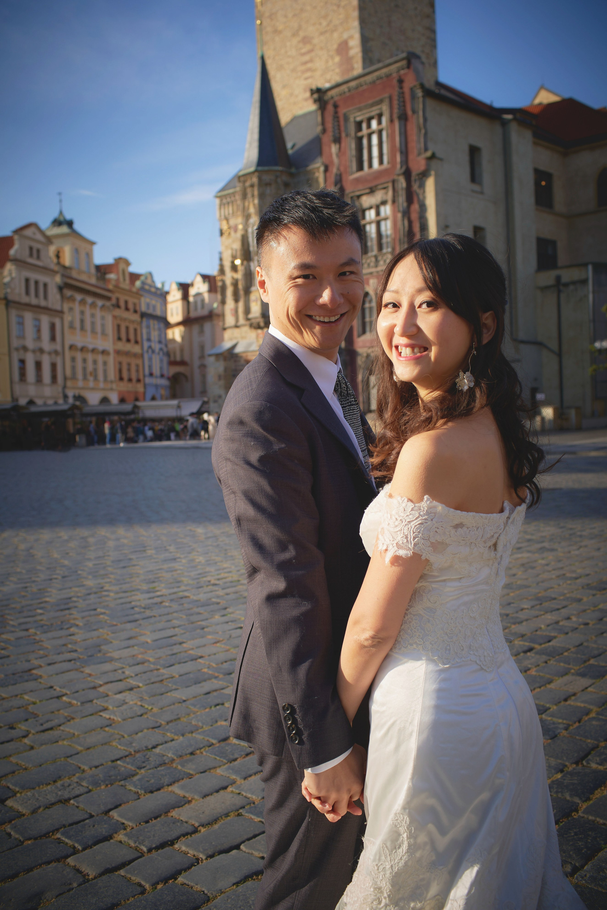 Playful smiling newlyweds Eva and Conan with Old Town Hall in the background, Prague.