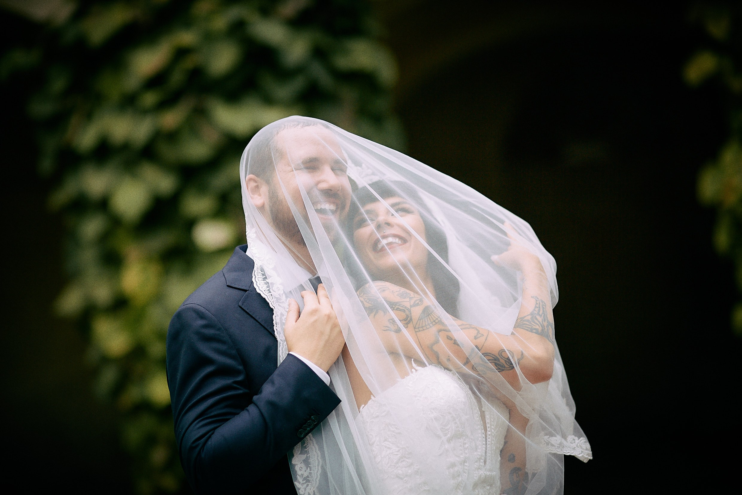 Bride draping veil romantically over groom in Grebovka cave setting.