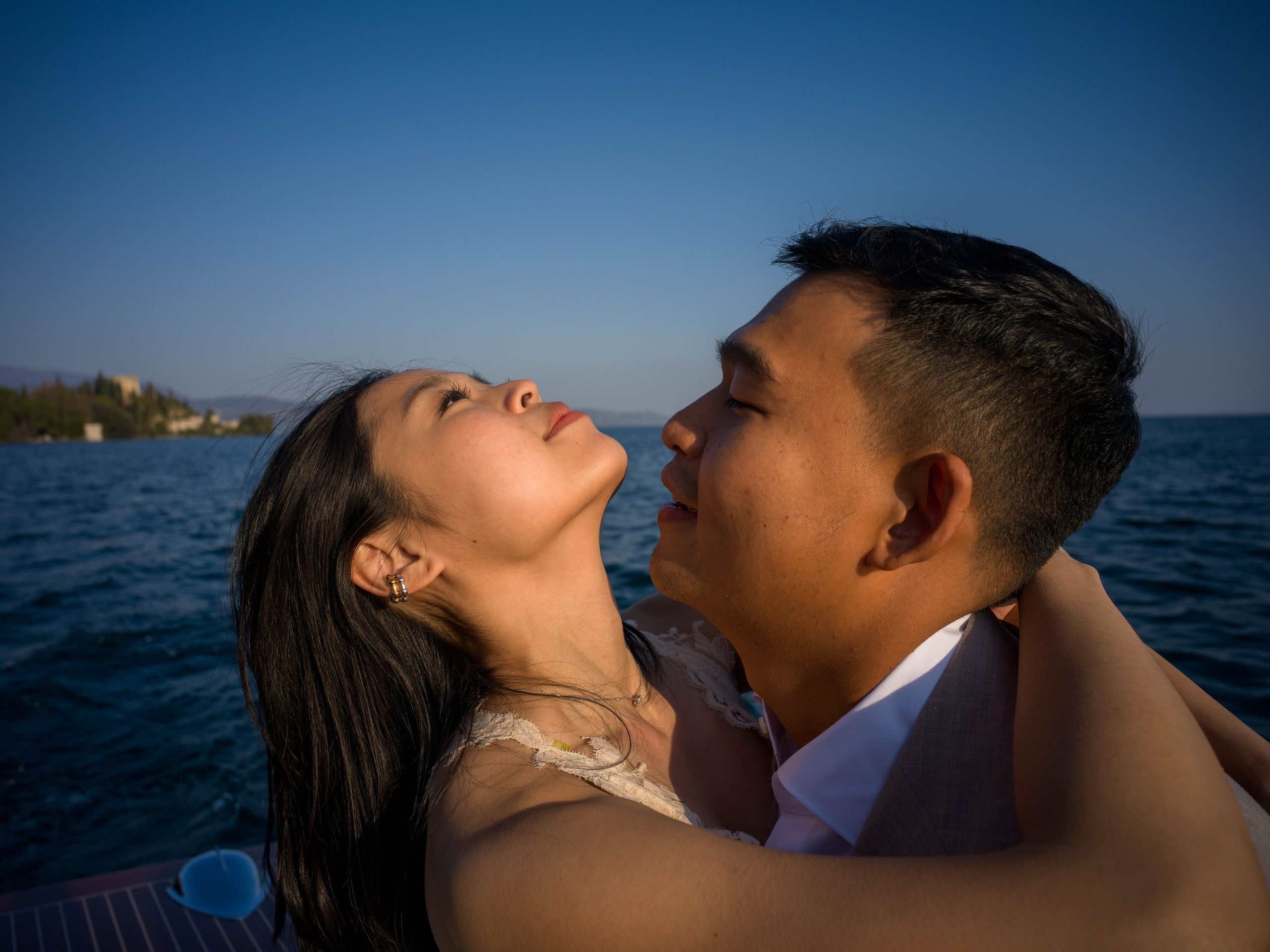 Couple celebrating engagement with Isola del Garda in the background.