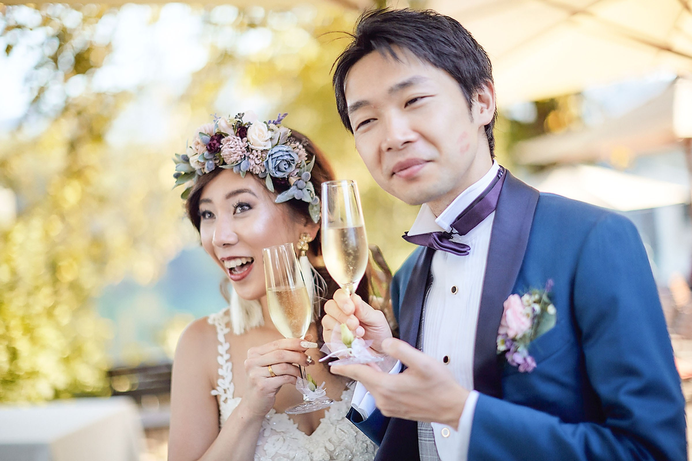 Japanese newlyweds enjoy champagne in an outdoor setting.