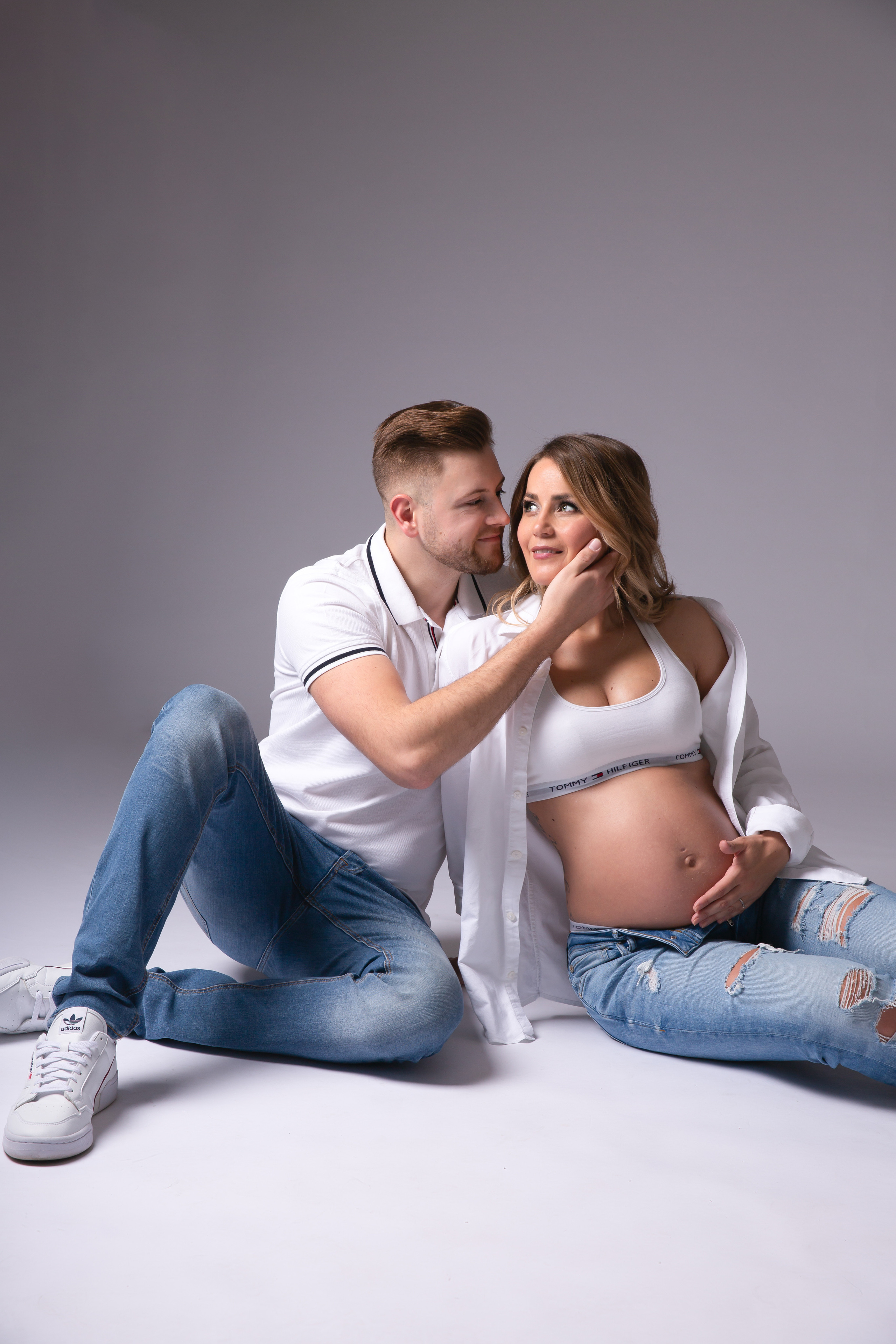 Entspanntes Babybauchfoto einer schwangeren Frau in Jeans und Top, fotografiert im Studio in Iserlohn.