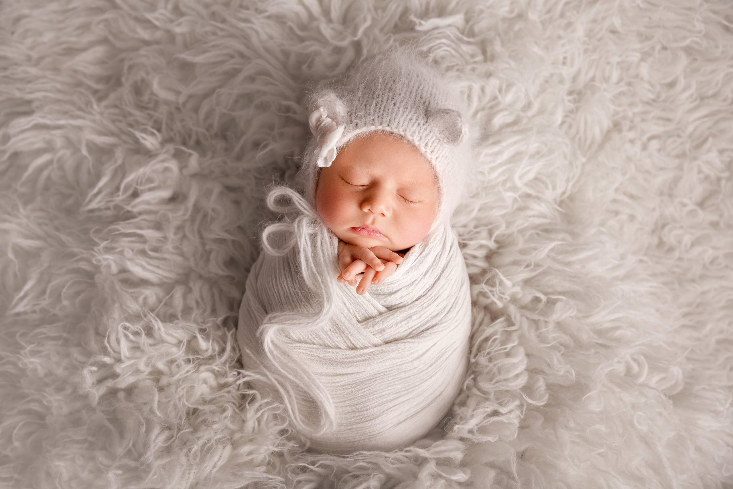 Frisch geborenes Baby eingewickelt in eine Decke, liegt in einem rustikalen Körbchen – Newbornfotografie in Iserlohn