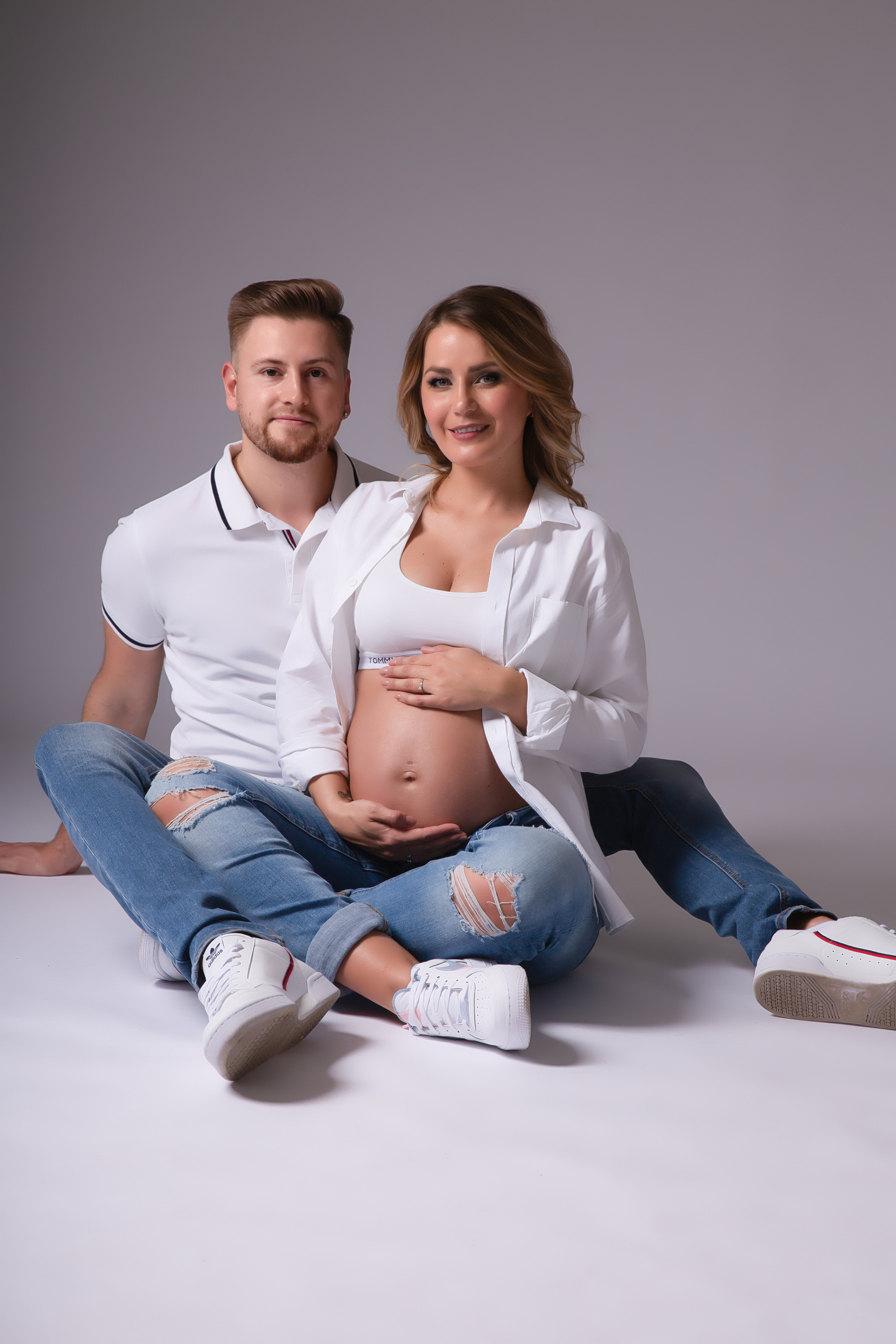 Entspanntes Babybauchfoto einer schwangeren Frau in Jeans und Top, fotografiert im Studio in Iserlohn.