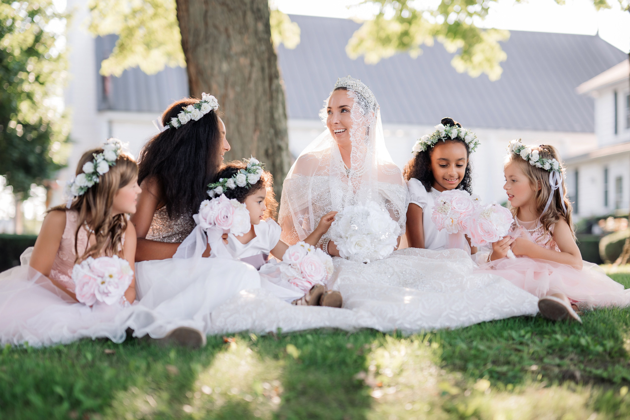 a bride and her bridesmaids sitting on the grass
