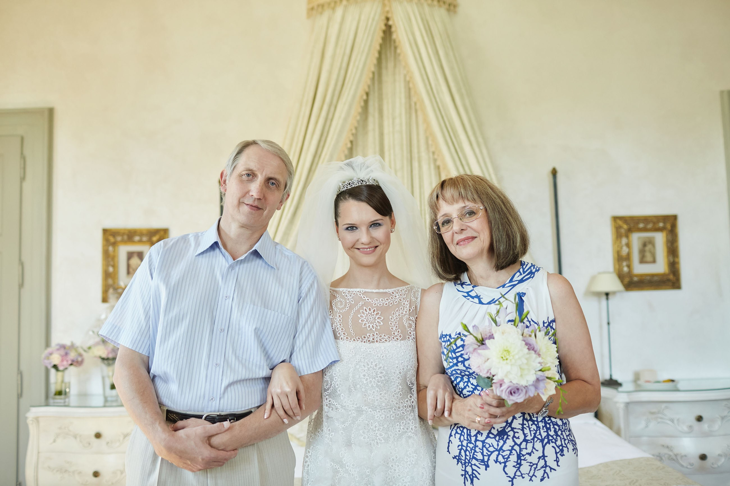 A father, bride, and mother pose for a photo in the bridal suite of the historic Chateau Mcely before the wedding ceremony.