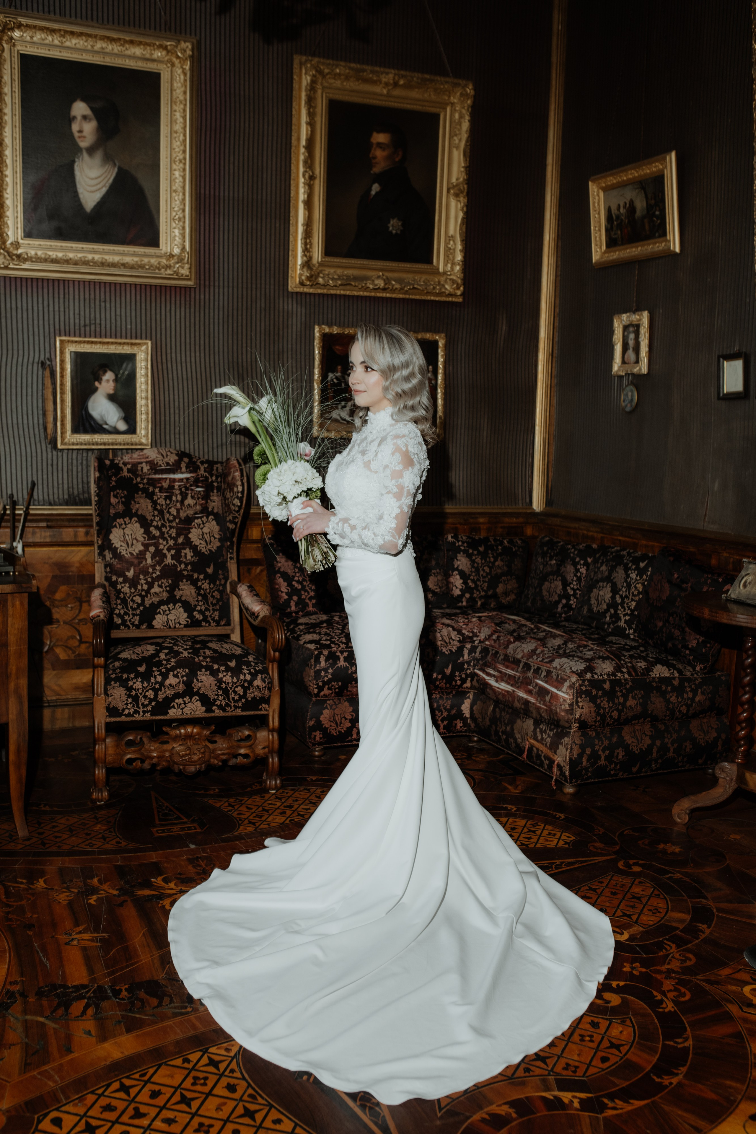 Braut Celine in ihrem eleganten Hochzeitskleid, umgeben von blühenden Blumen im Schlossgarten.
