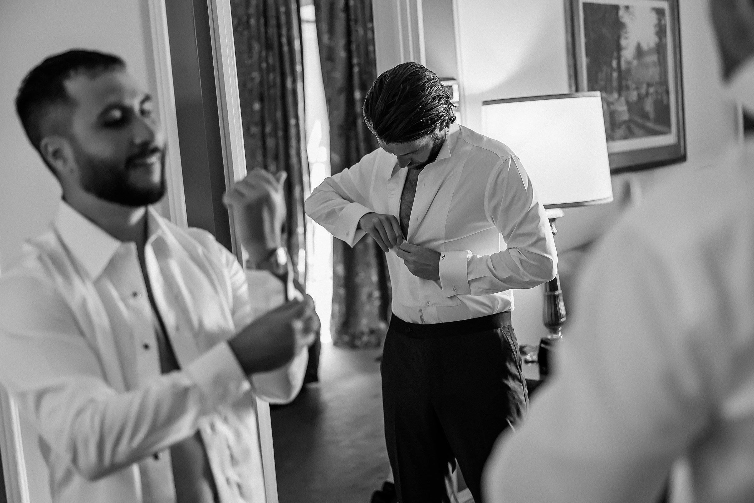 The groom, dressed in formal attire, gets ready for his wedding in a grand hotel room, surrounded by luxury interior.