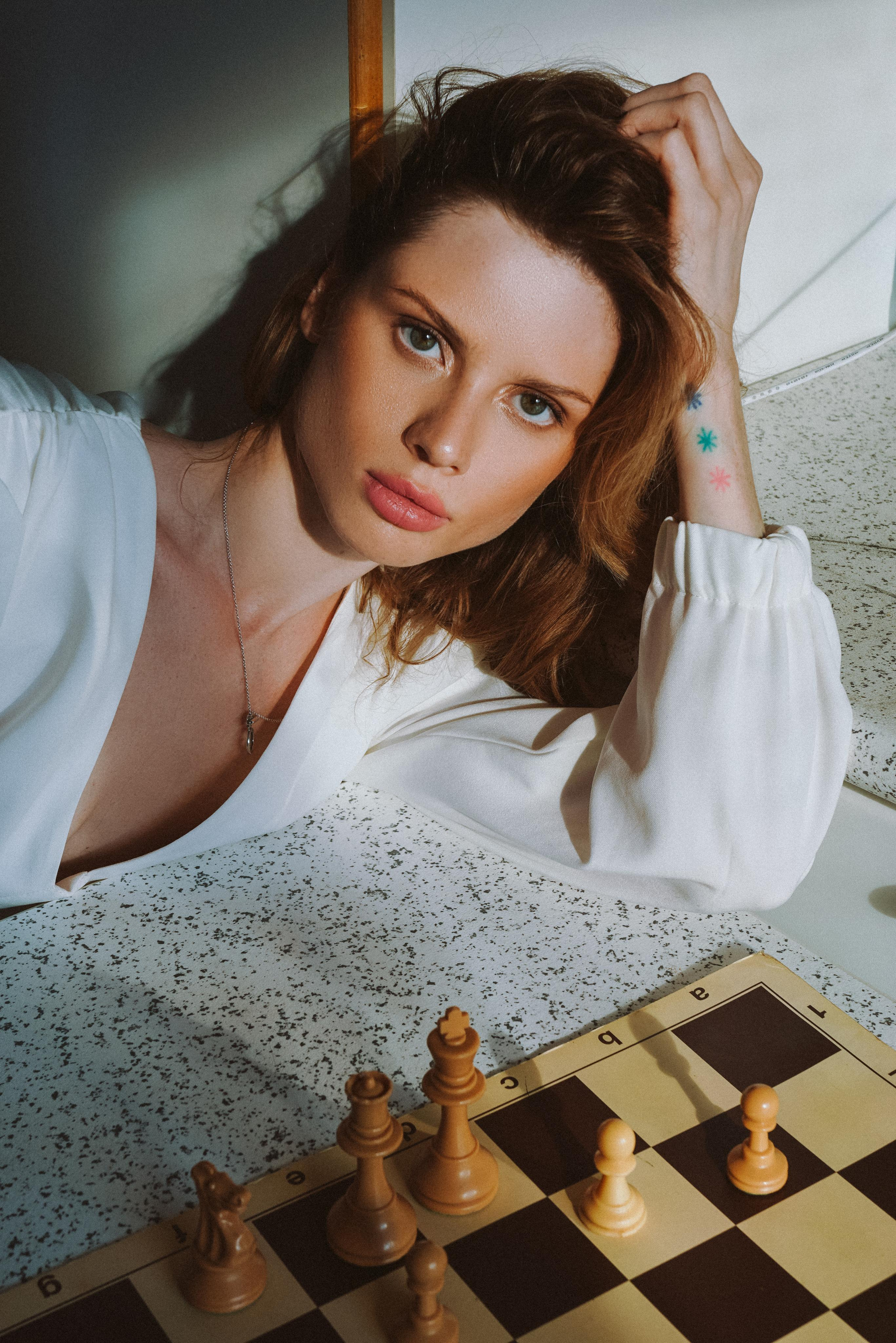 a model with bronze makeup posing in front of a chess board