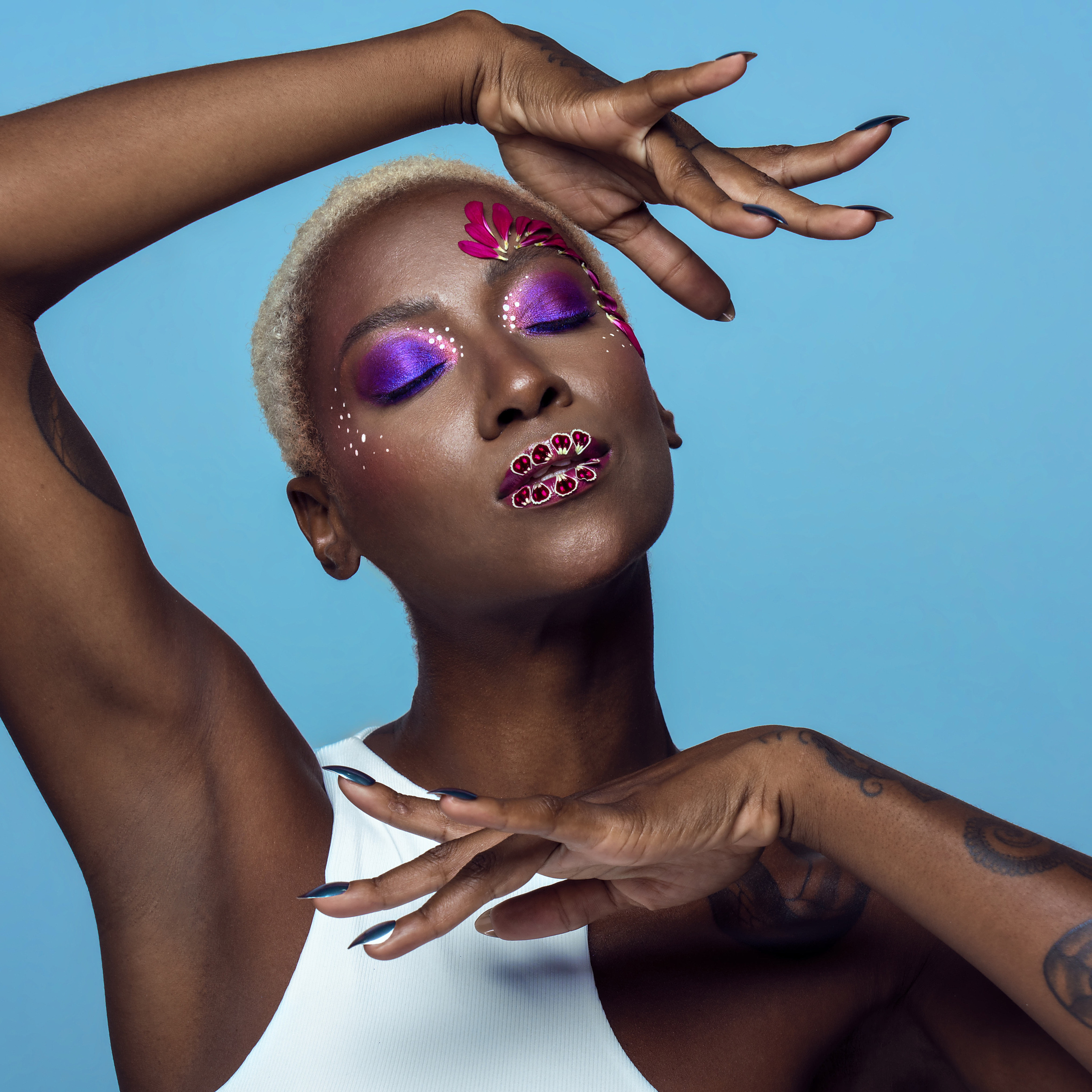 black woman with bright colorful makeup and real flowers on her face posing in a photostudio in venice