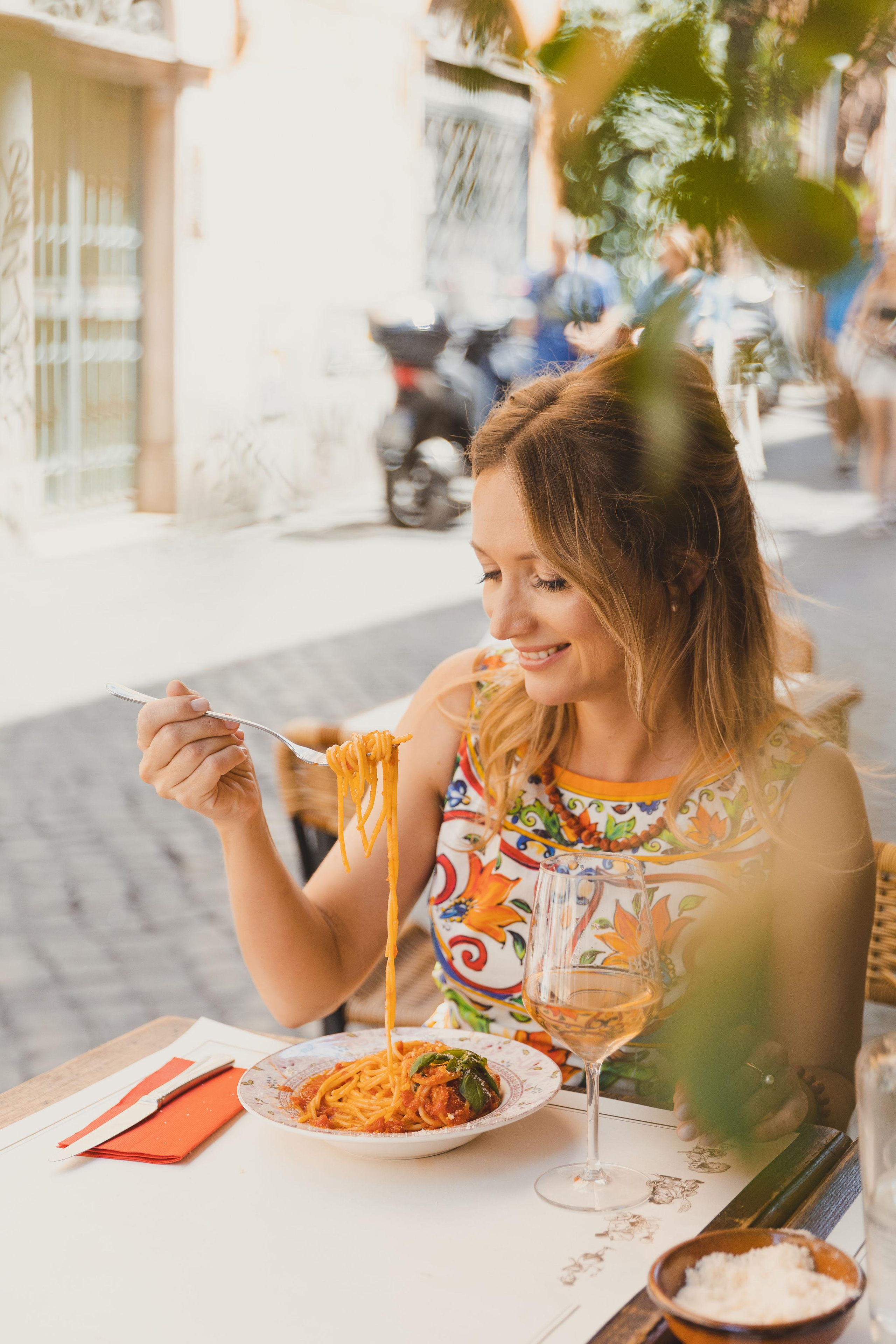 a woman eating pasta in a restaurant outside