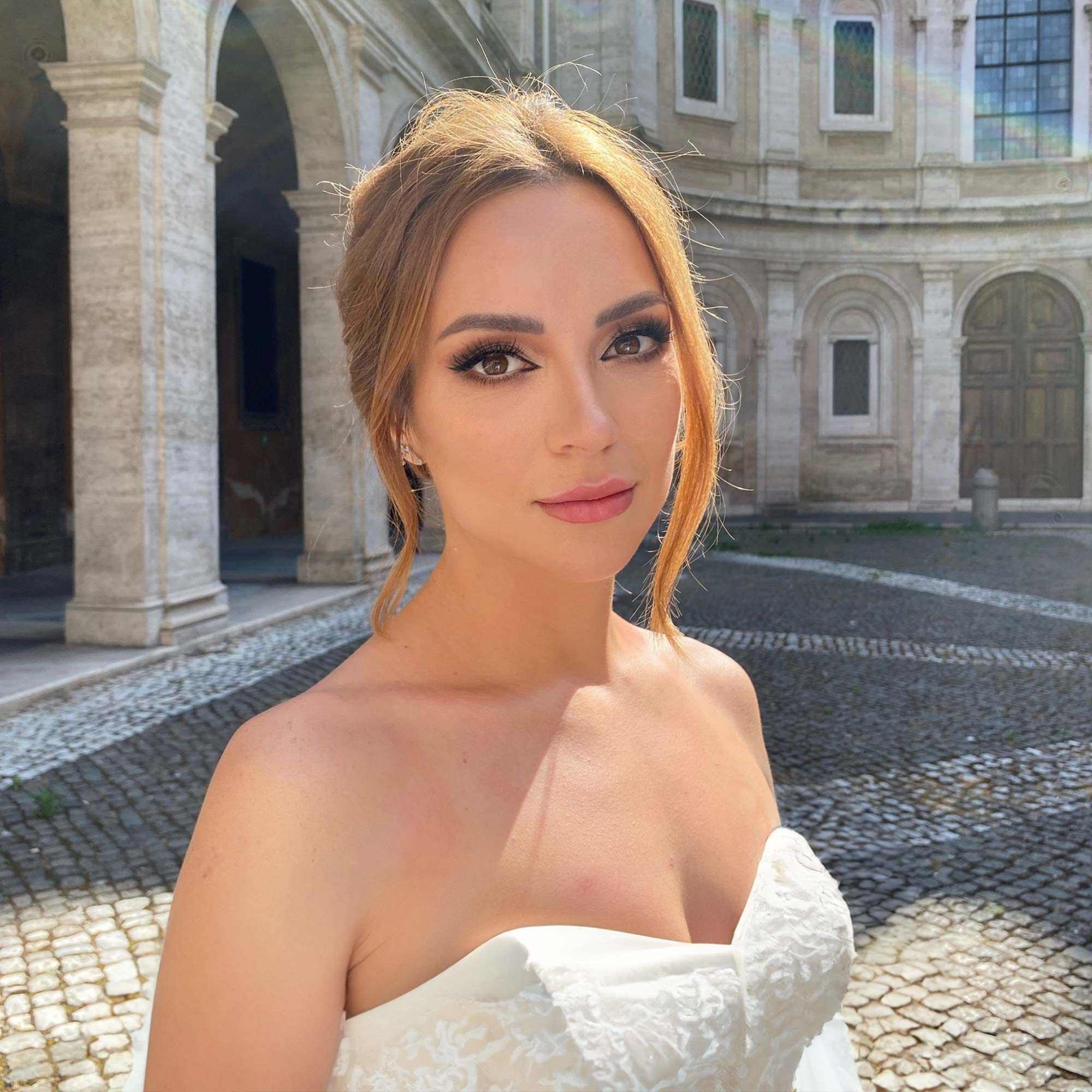 a bride with wedding makeup and bridal hairstyle posing inside old building in rome