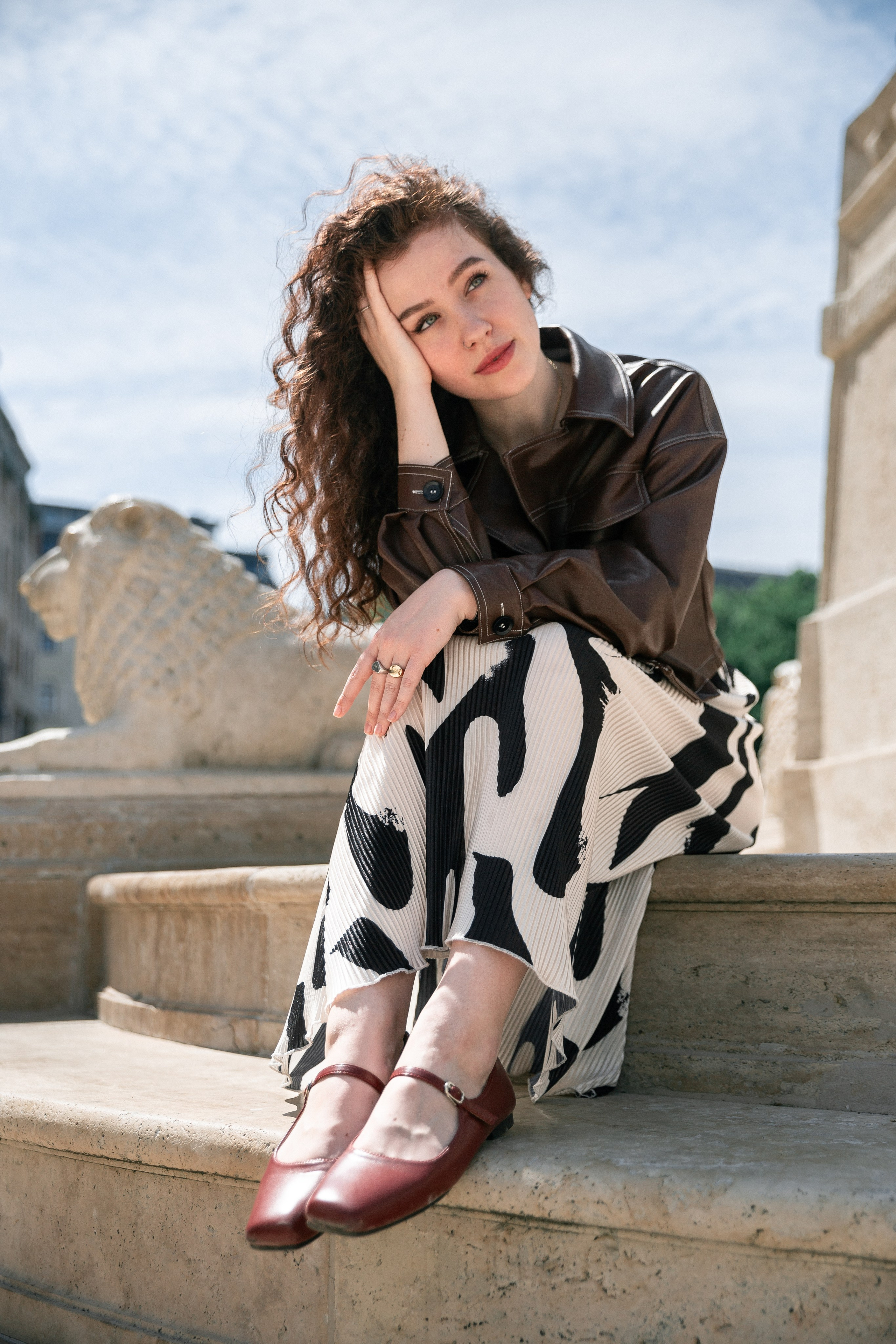 a photo of a red-haired girl sitting by a fountain in Budapest