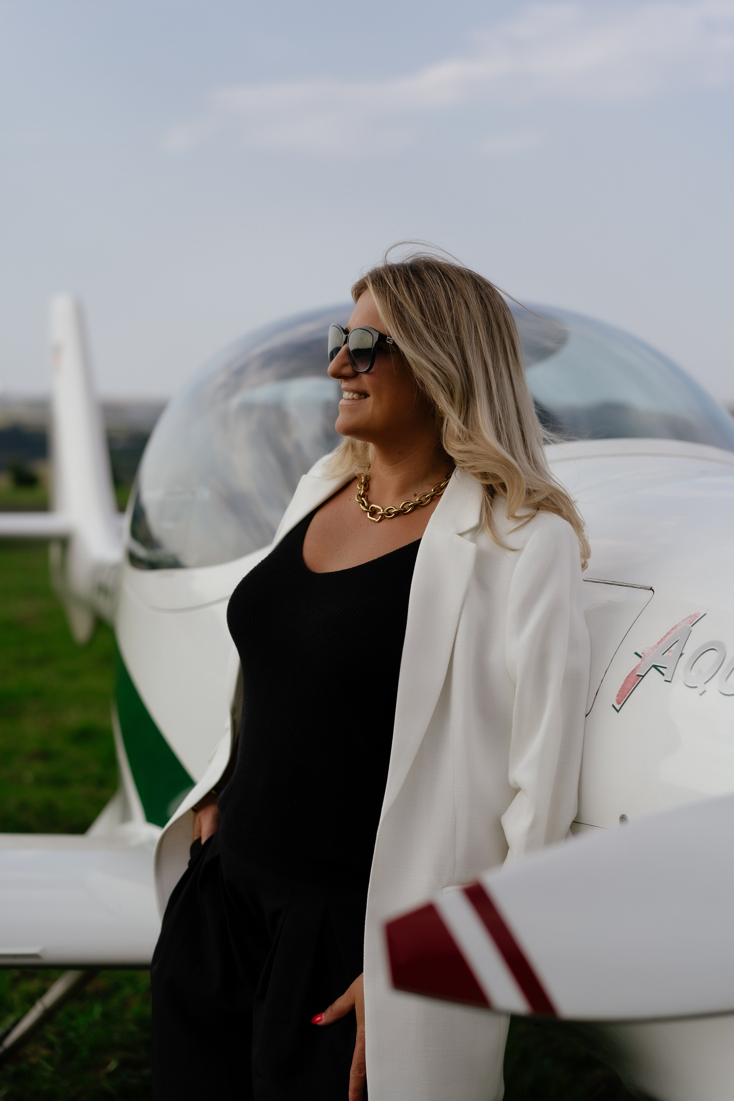 Elegantes Frauenporträt vor einem Flugzeug auf dem Flugplatz