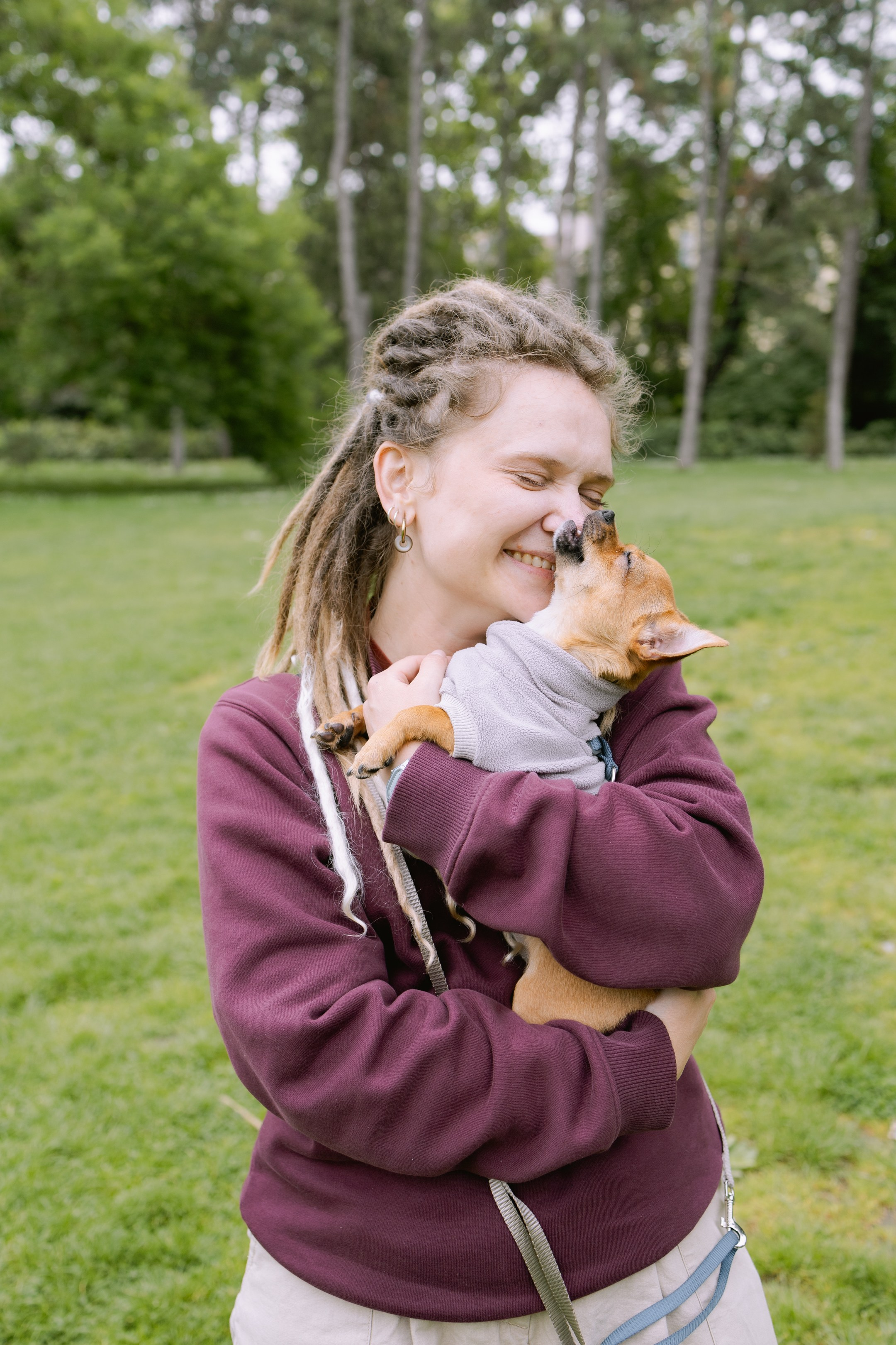 Юля смеётся, обнимая Роки, который игриво кусает её за нос.