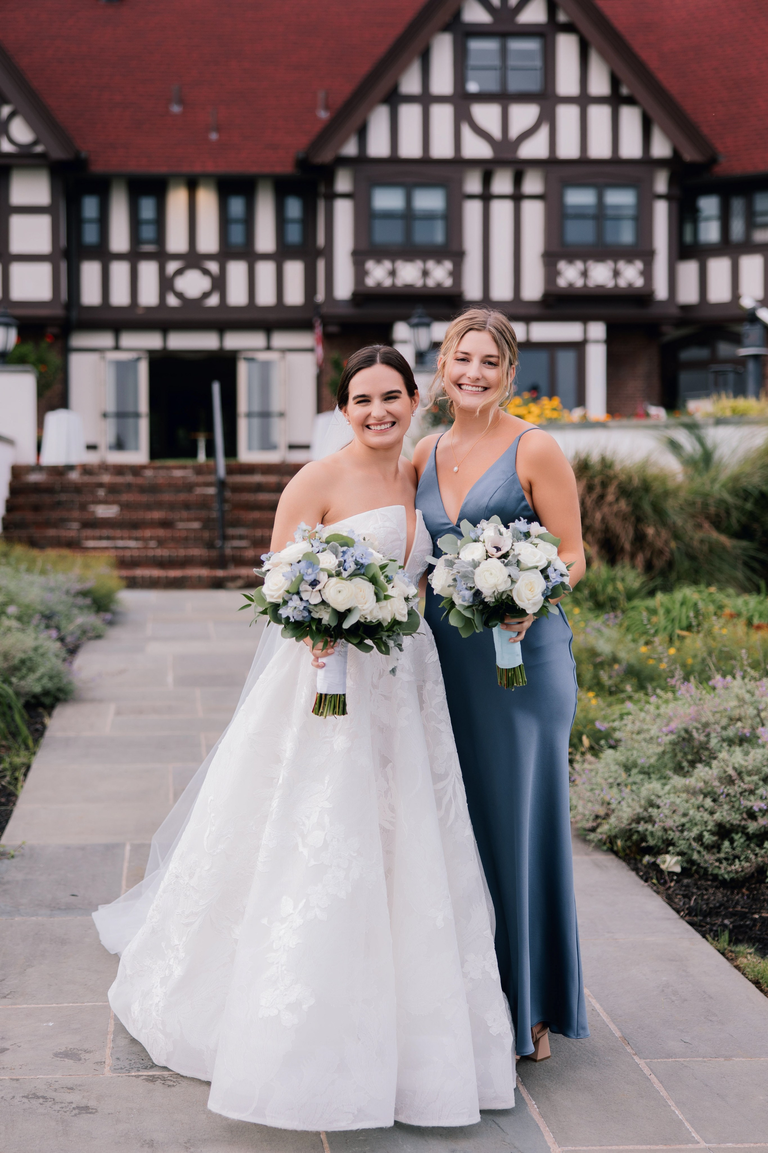 two brides pose for a photo in front of a house