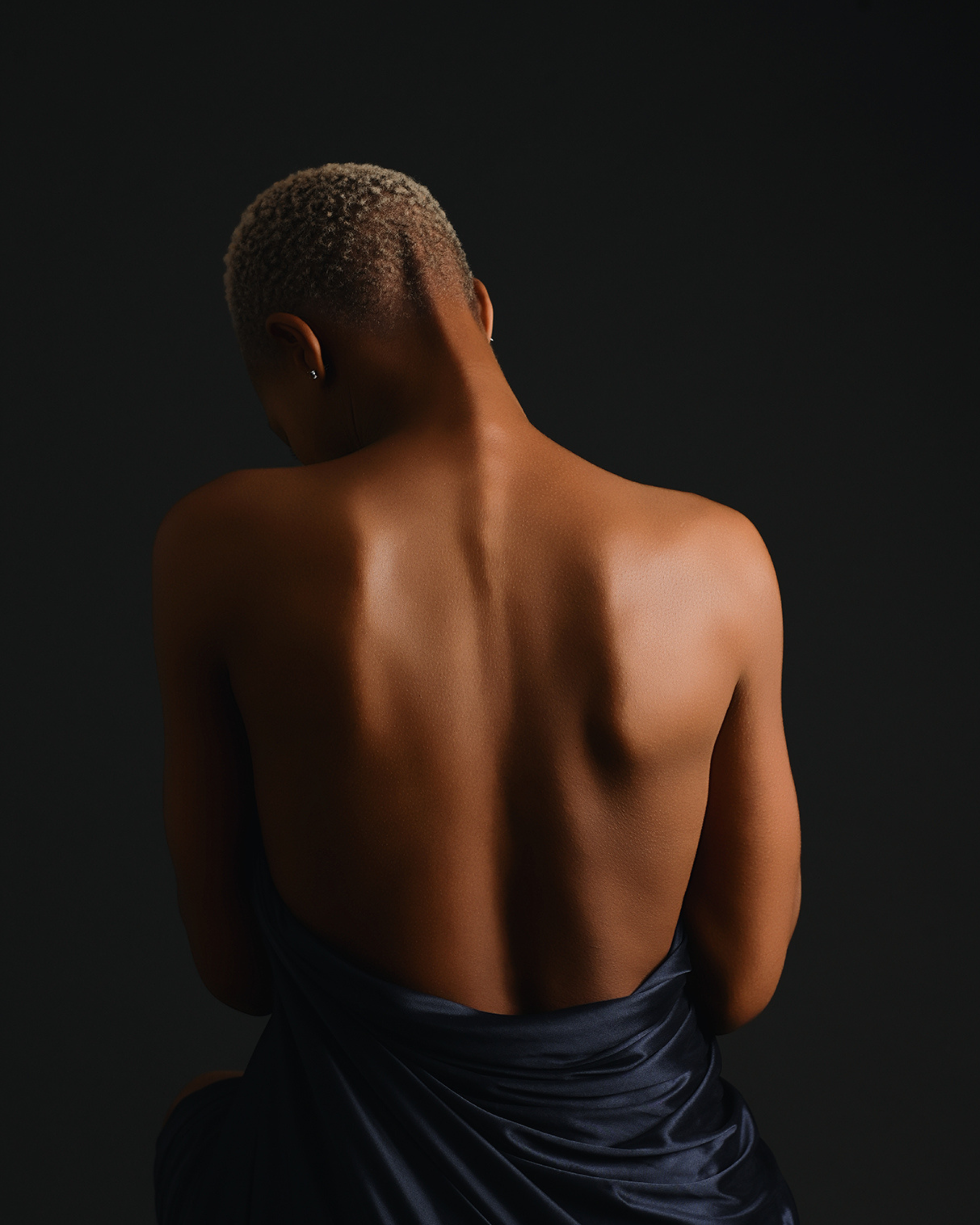 Ausdrucksstarkes Portrait einer Frau, das ihren freien Rücken zeigt– tiefe Emotionen, Persönlichkeit und natürliche Schönheit in kunstvoller Lichtsetzung eingefangen.