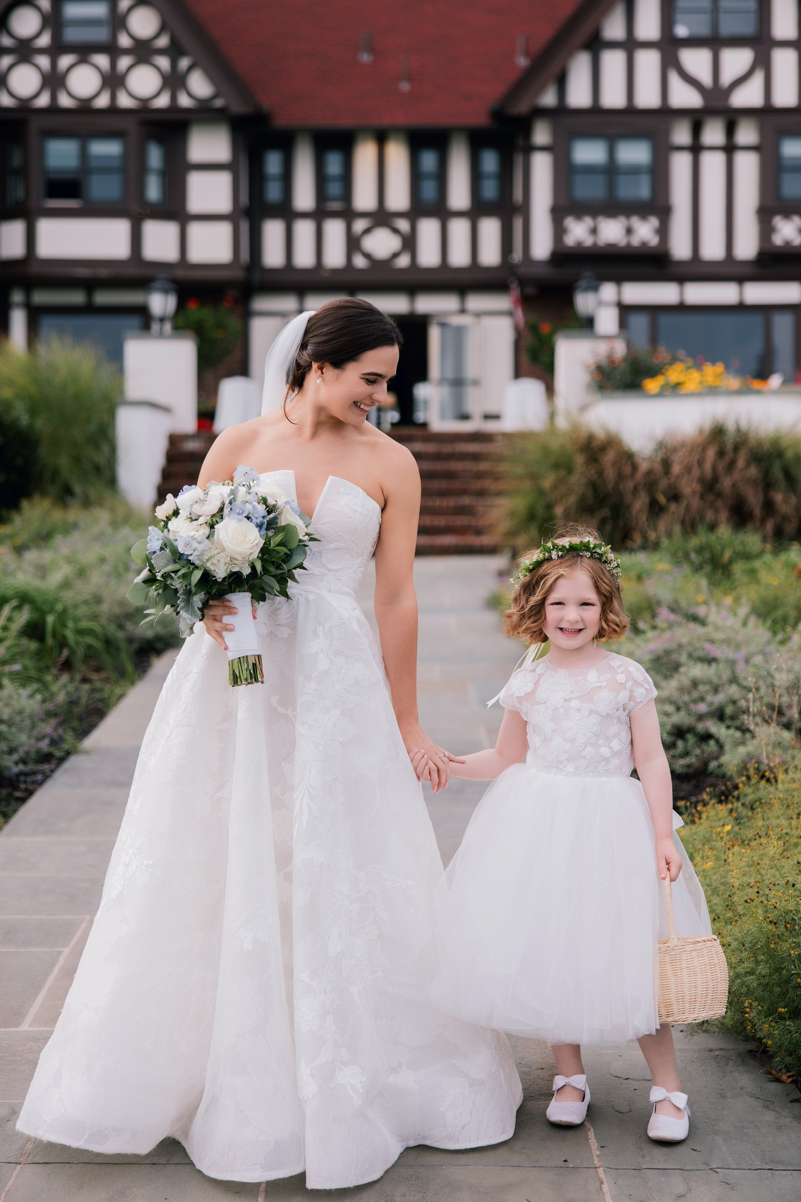 a bride and her flower girl walking down the sidewalk