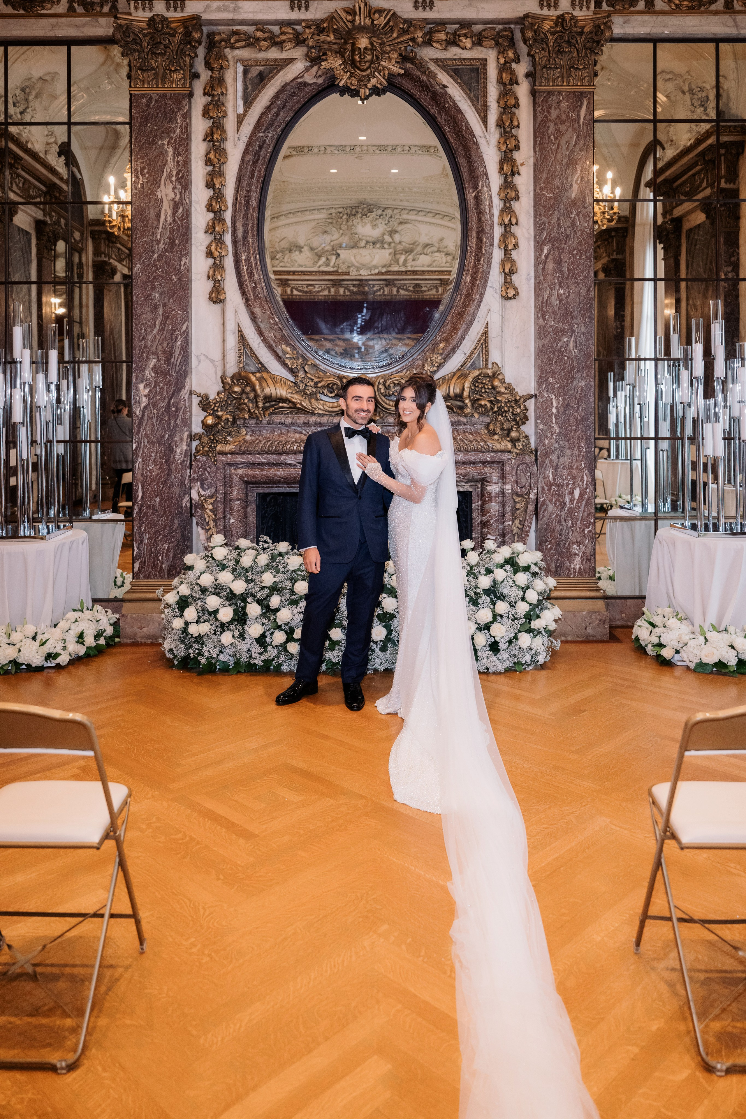 a bride and groom pose for a photo in front of a fireplace