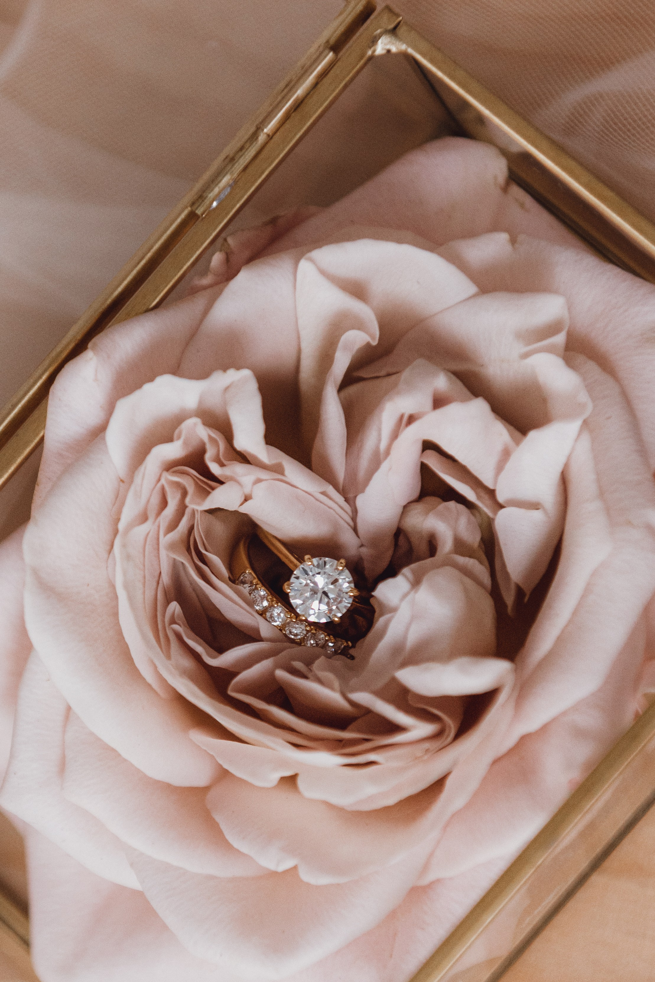 Newlyweds embracing during a sunset wedding shoot in Espoo. Wedding rings and floral details photographed in a modern, artistic style.