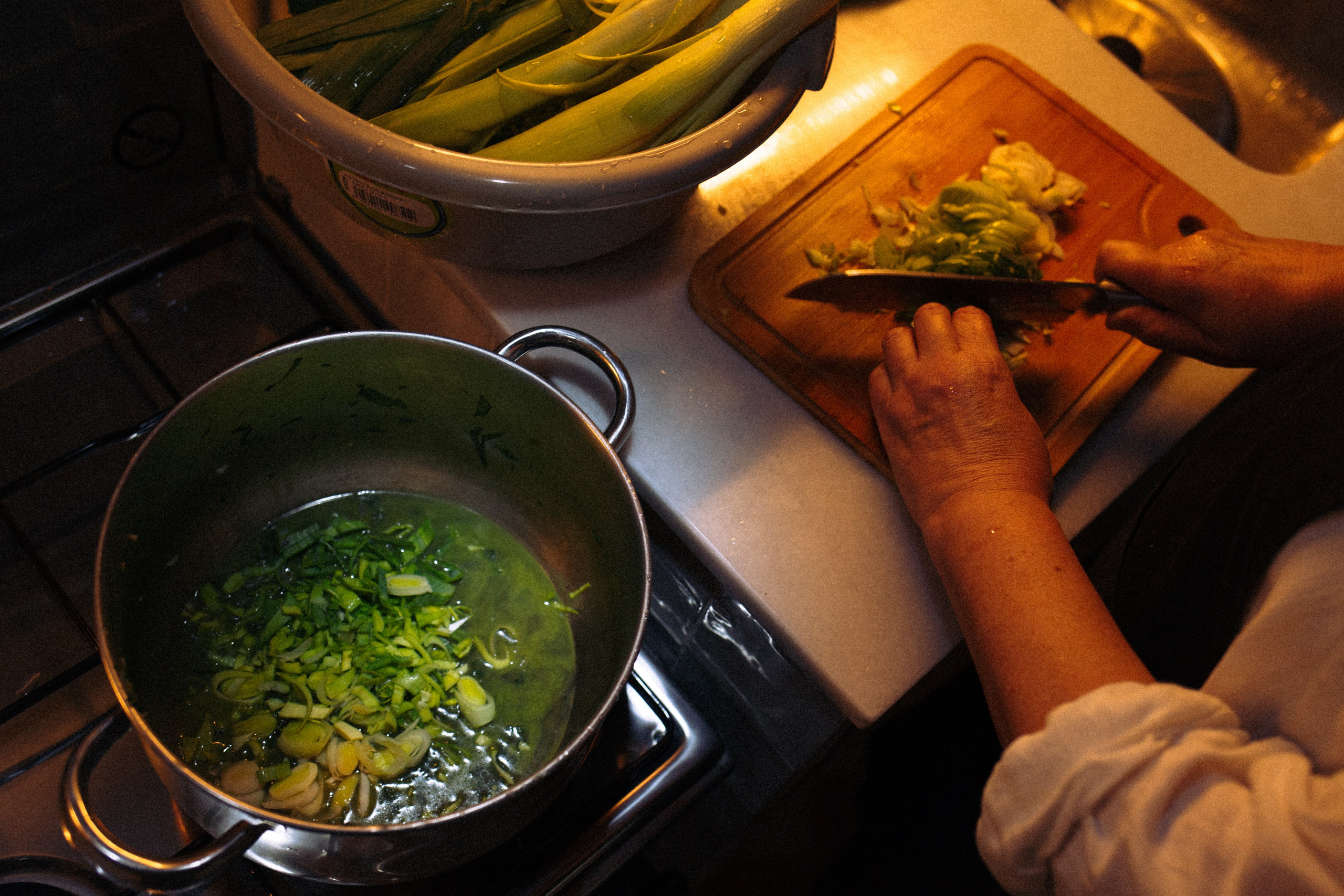 Close-up of hands chopping onions for soup in a warm, intimate kitchen setting with soft light