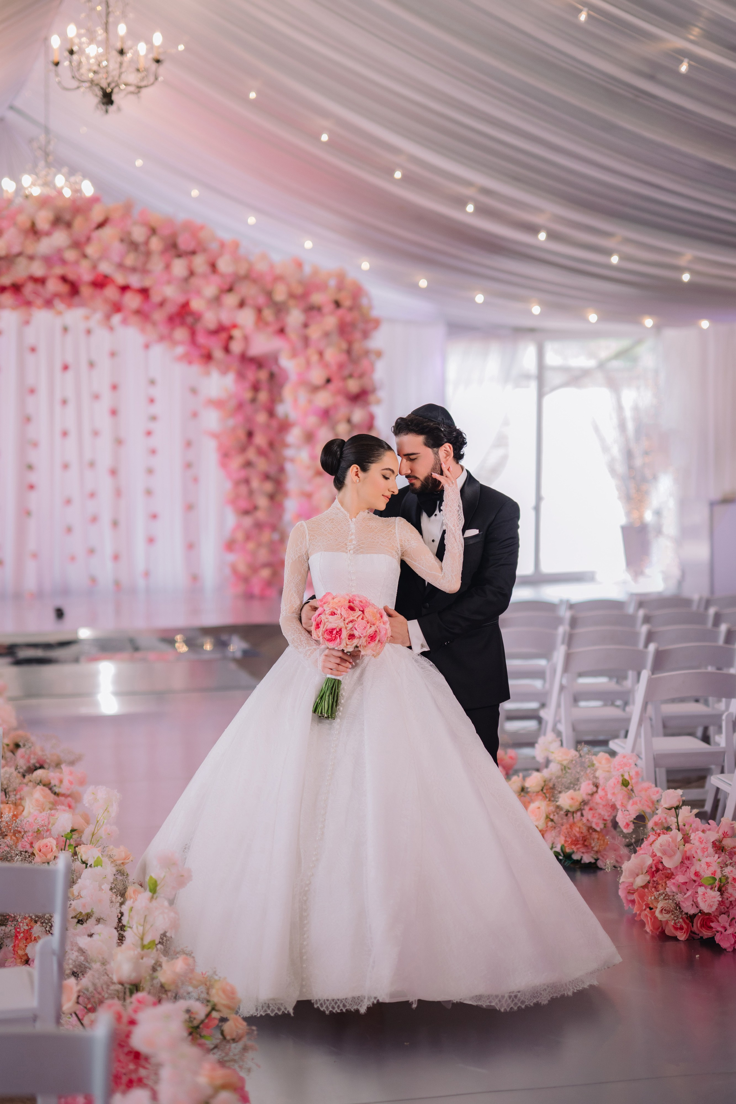 a bride and groom kissing in front of a floral arch