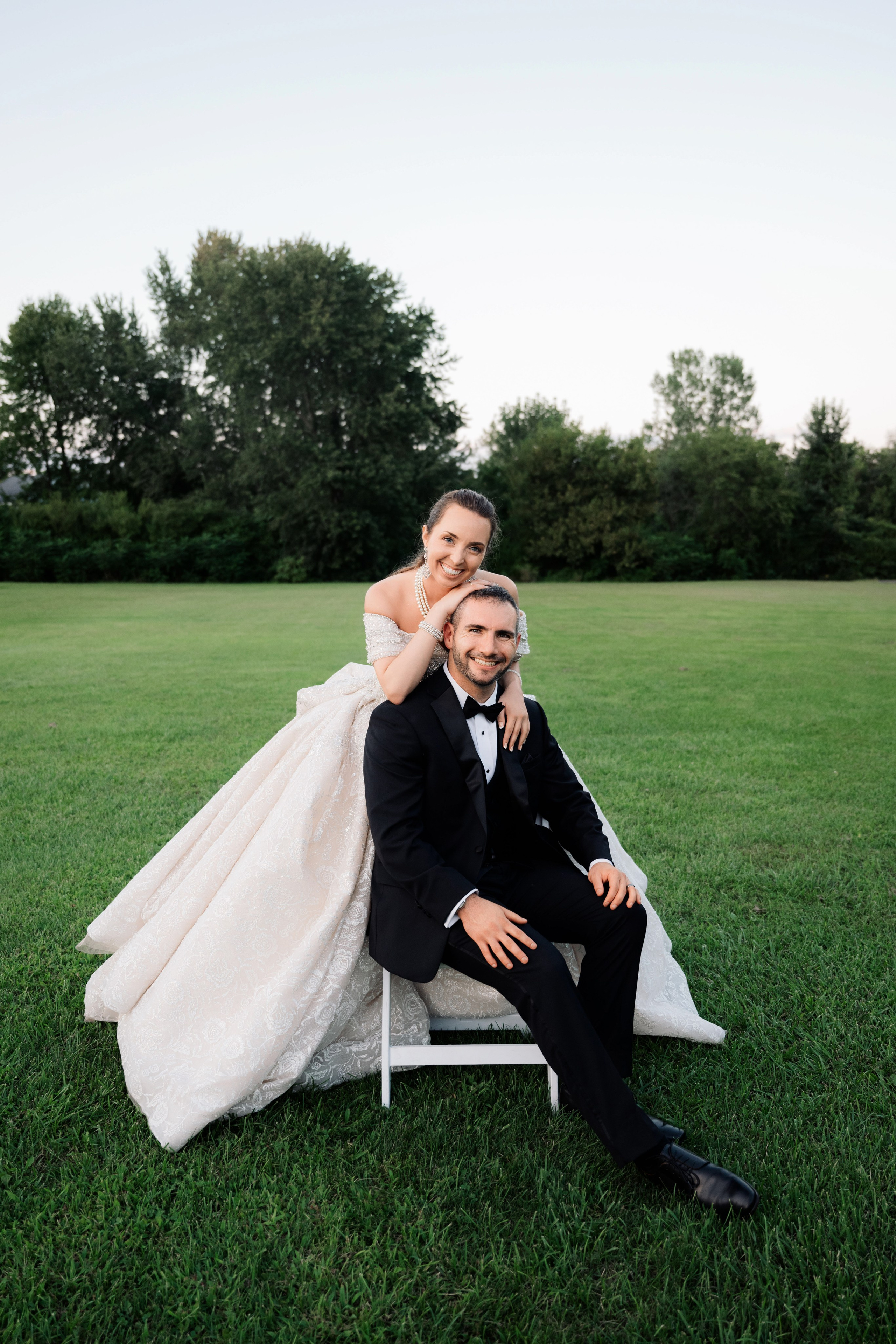 a bride and groom sitting on a lawn