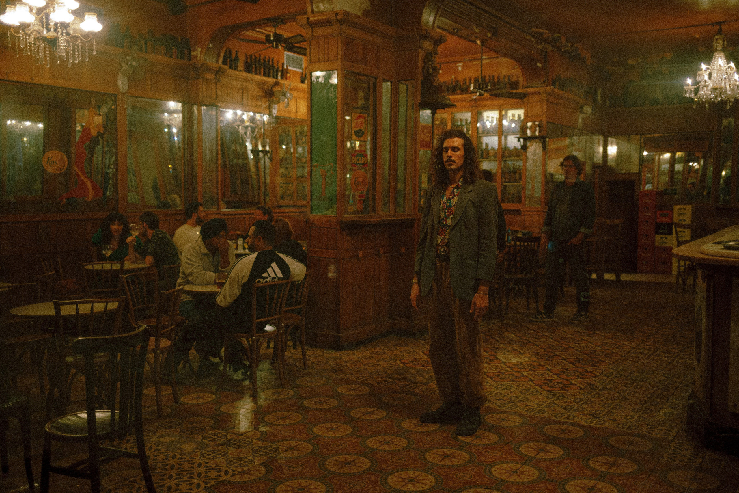 A vintage-style bar with a man standing and warm lighting