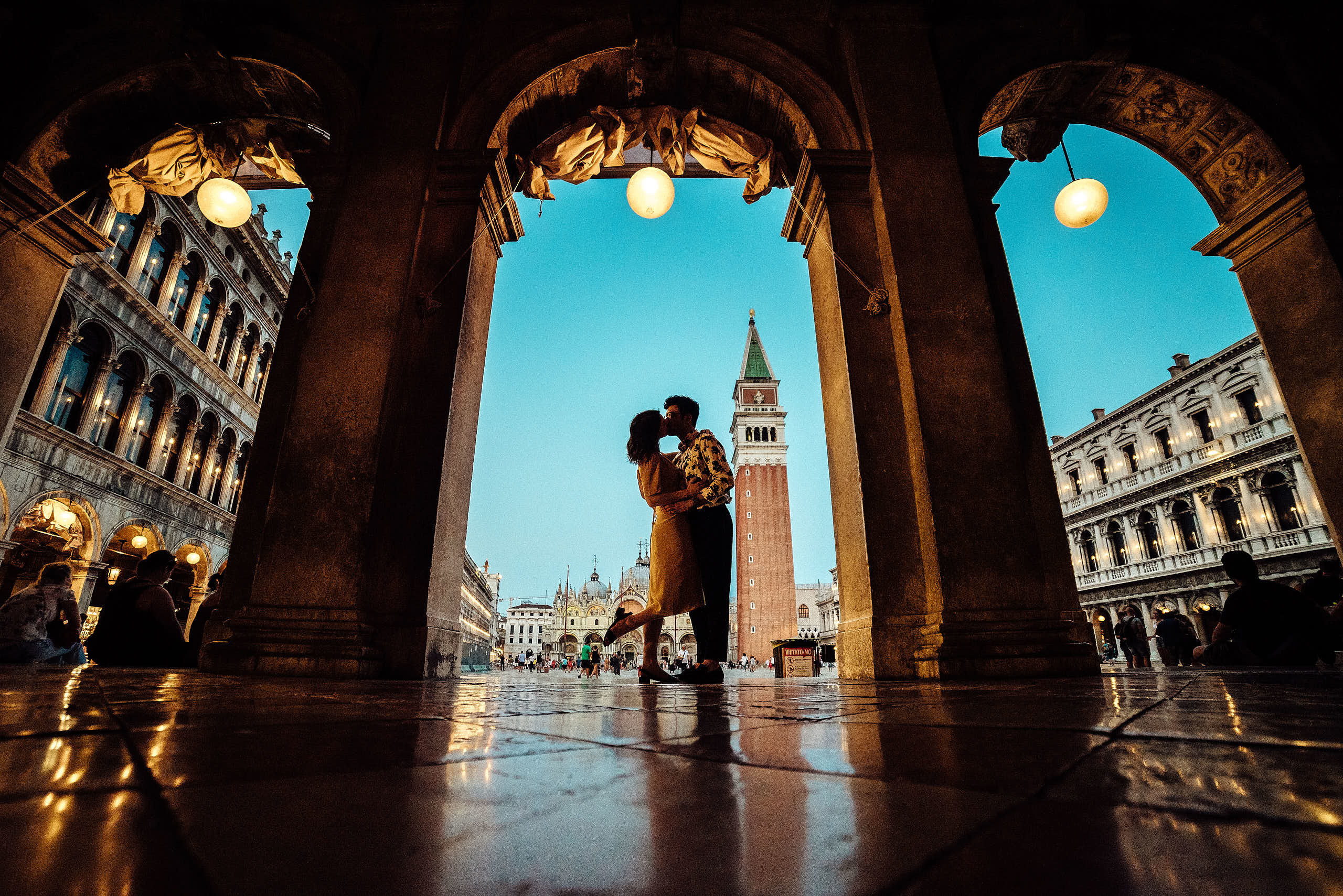 Lovers kissing under the arches with view on san Marco square, lovestory photosession in venice