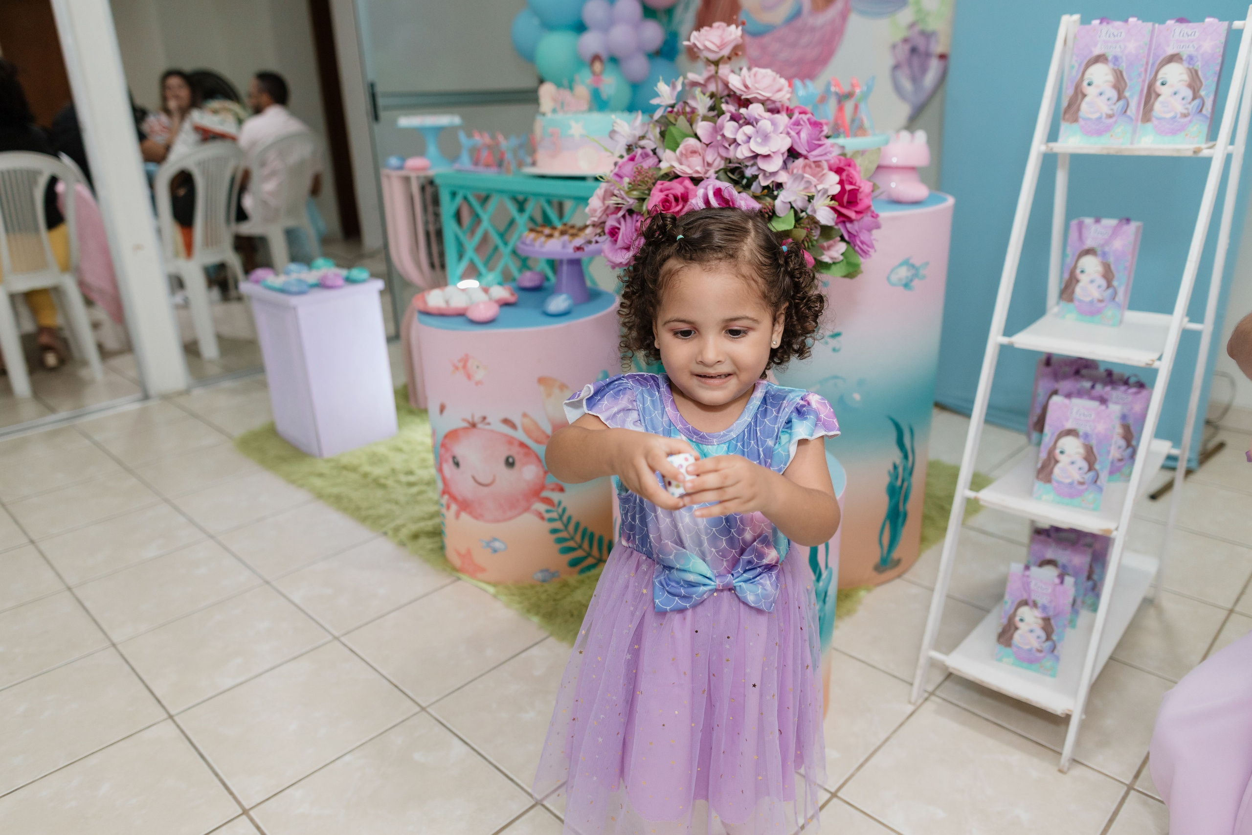Elisa em frente a mesa do bolo na festa infantil