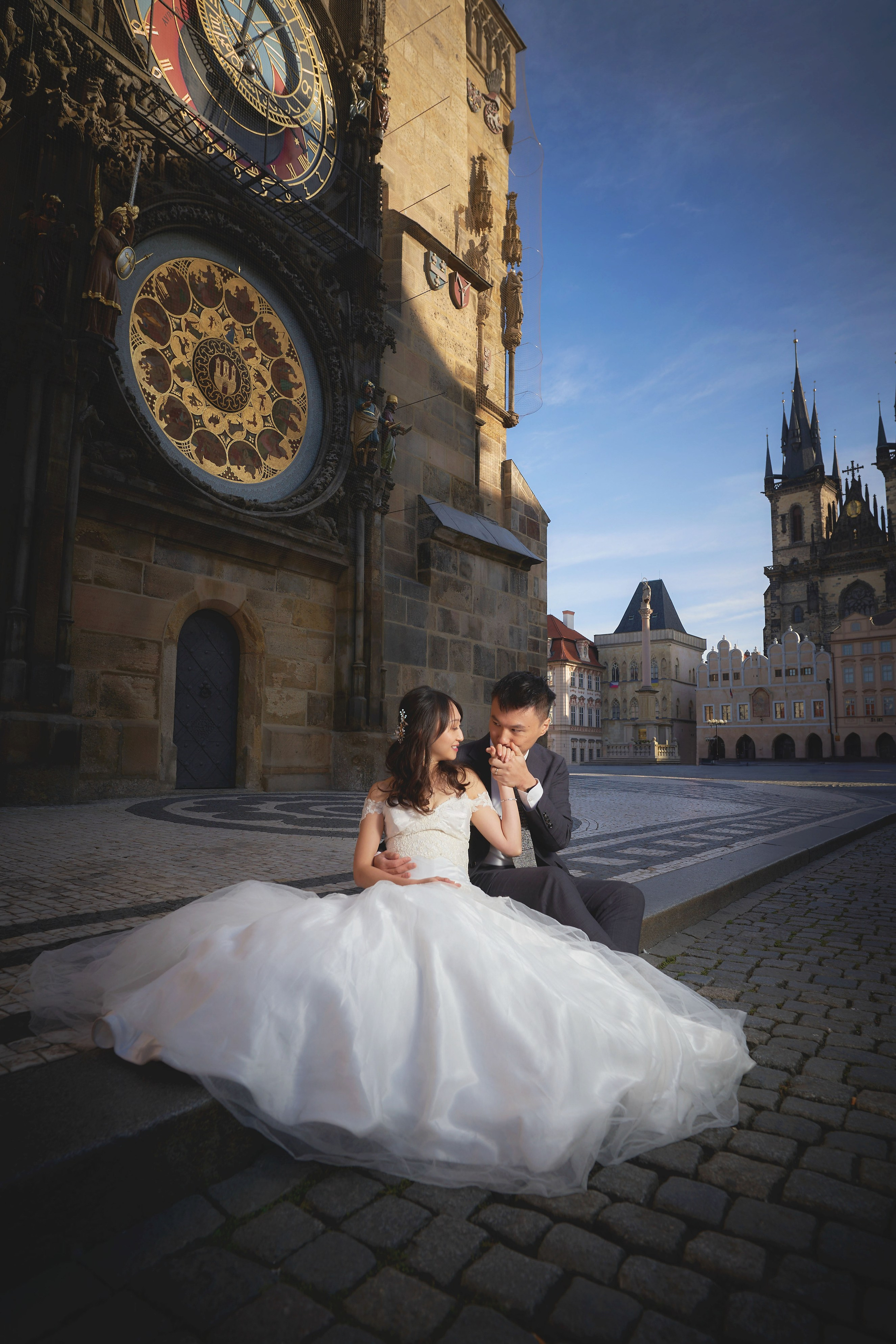 Groom Conan kissing bride Eva’s hand beneath the Astronomical Clock in Old Town Square.