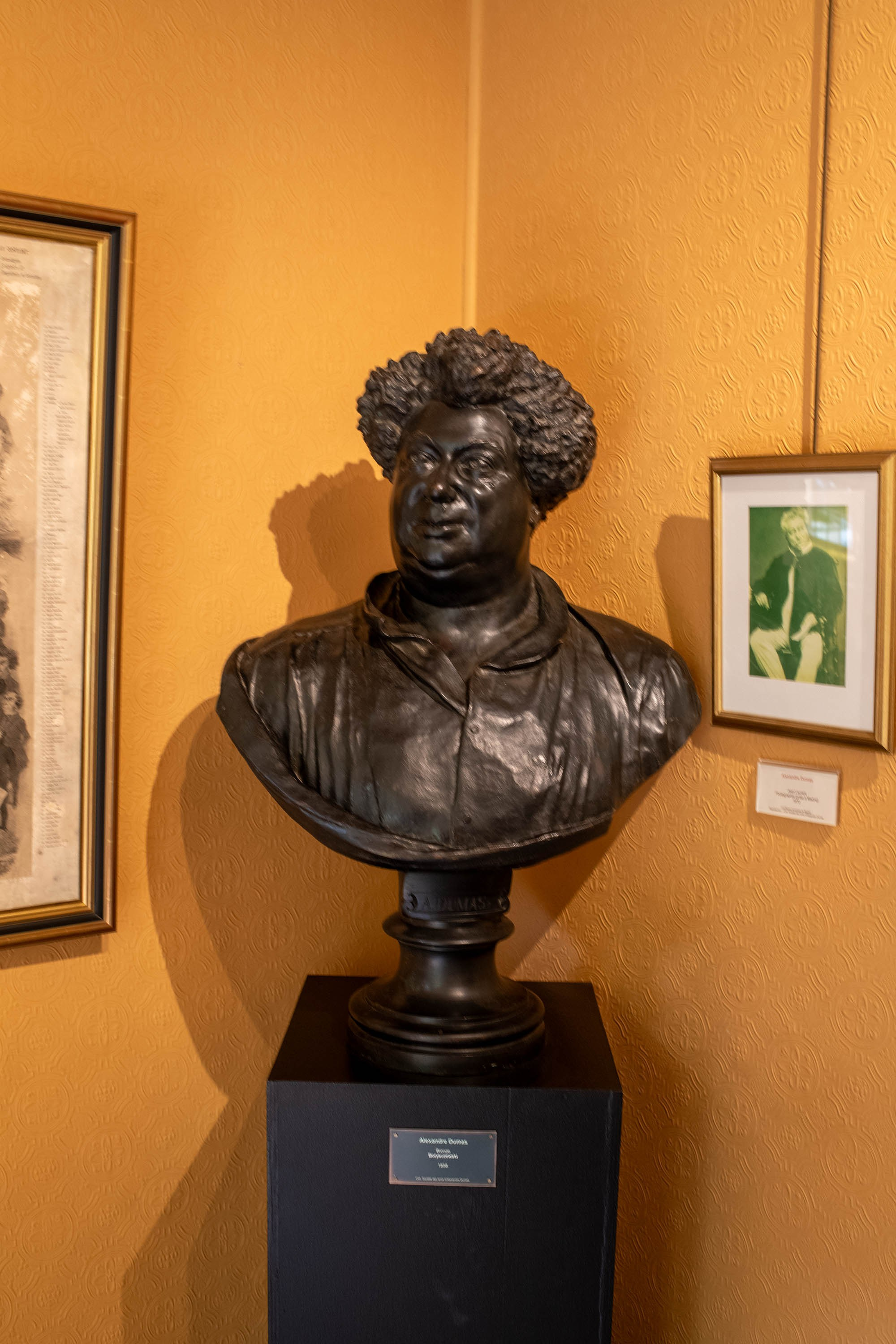 Bronze bust of Alexandre Dumas displayed on a pedestal inside the Château de Monte-Cristo museum in France.