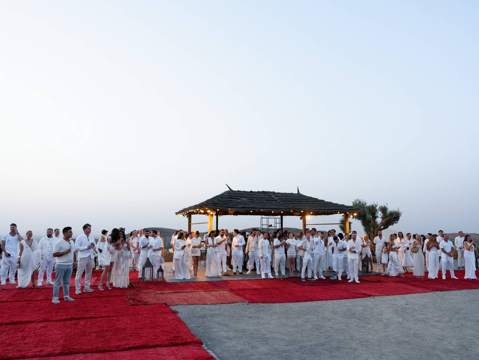 Wedding guests gathered by pavilion at destination desert reception, Morocco