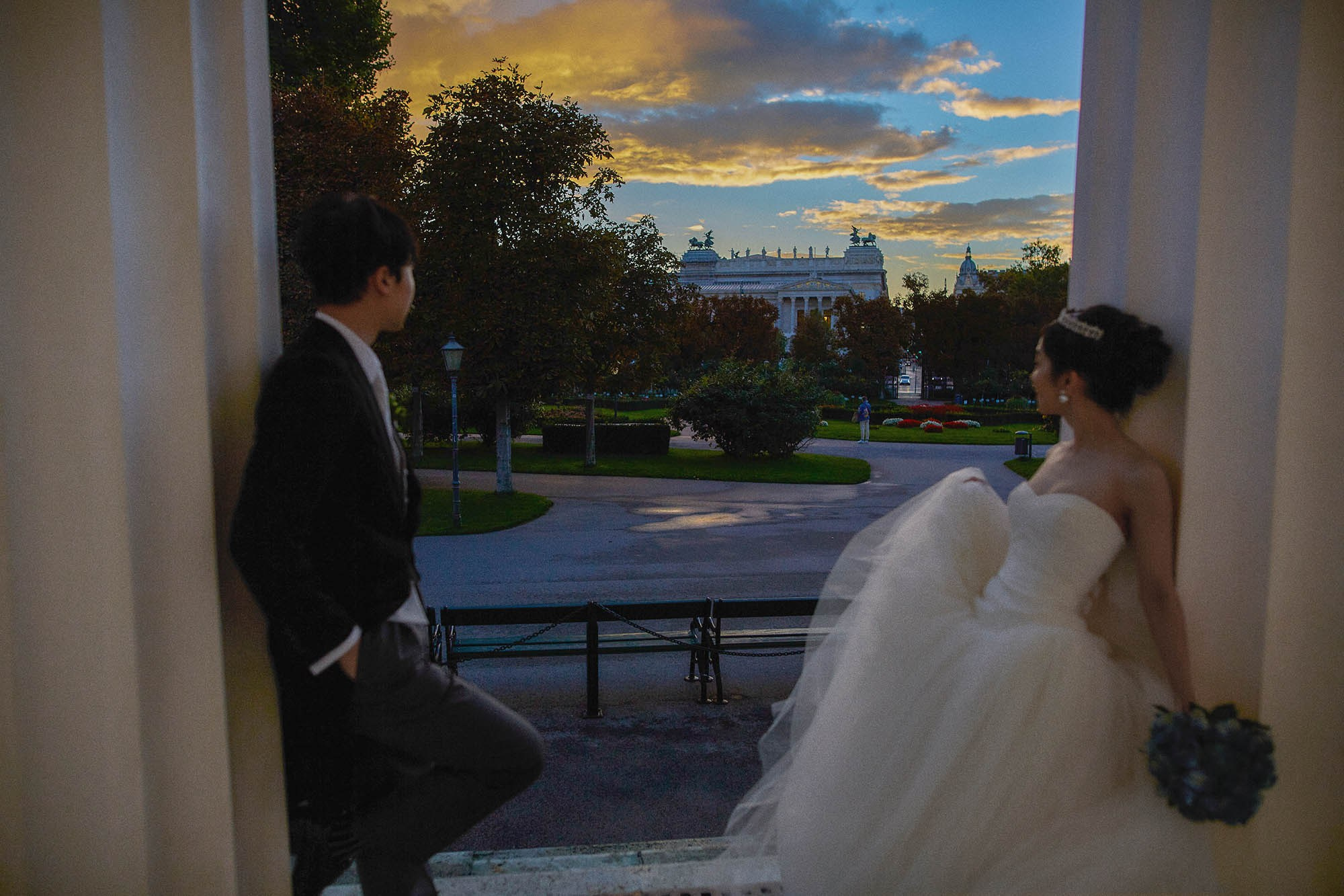 Newlyweds watching sunset near monument Volksgarten Vienna.