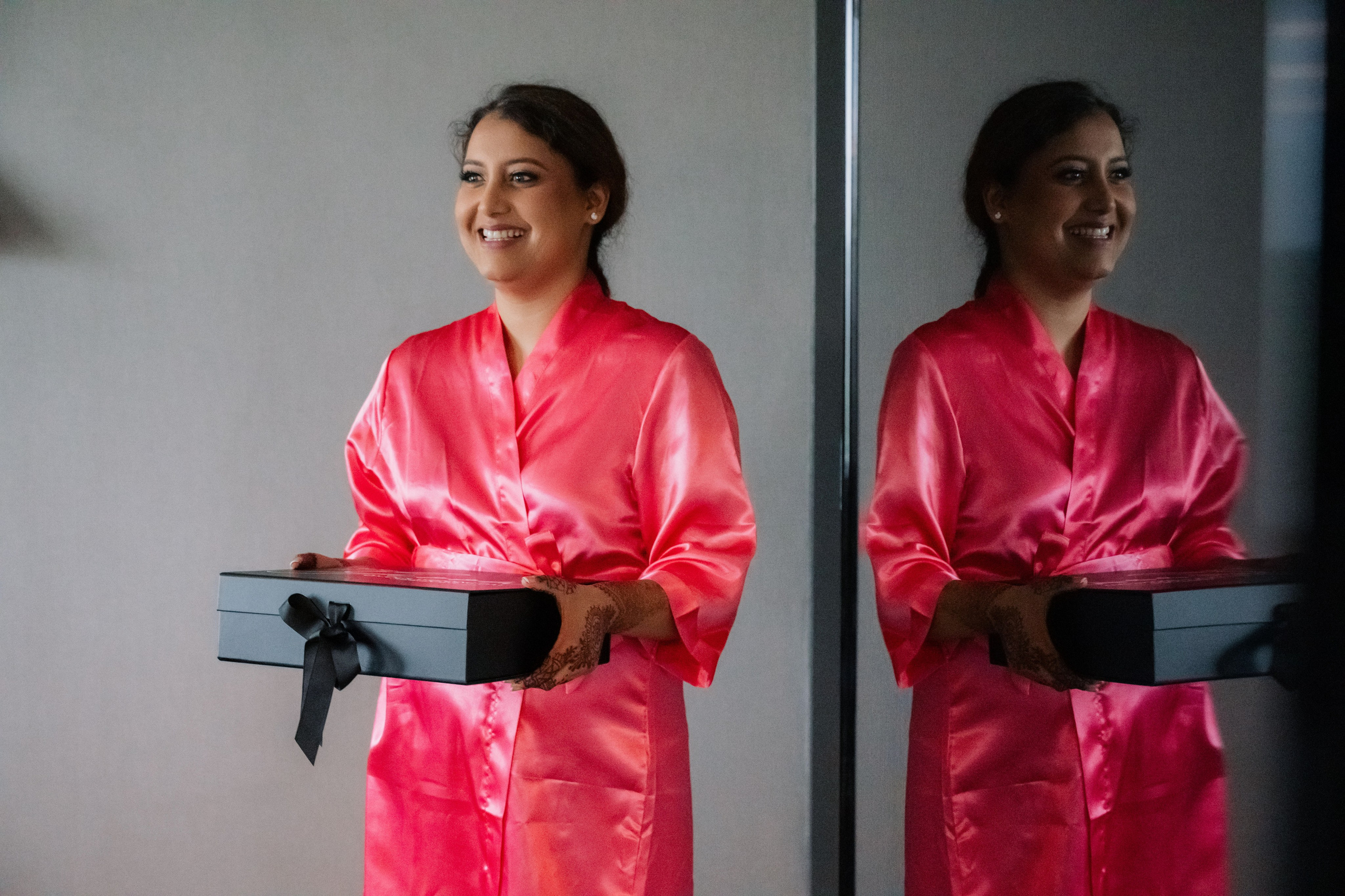 a woman in a pink robe holding a black box
