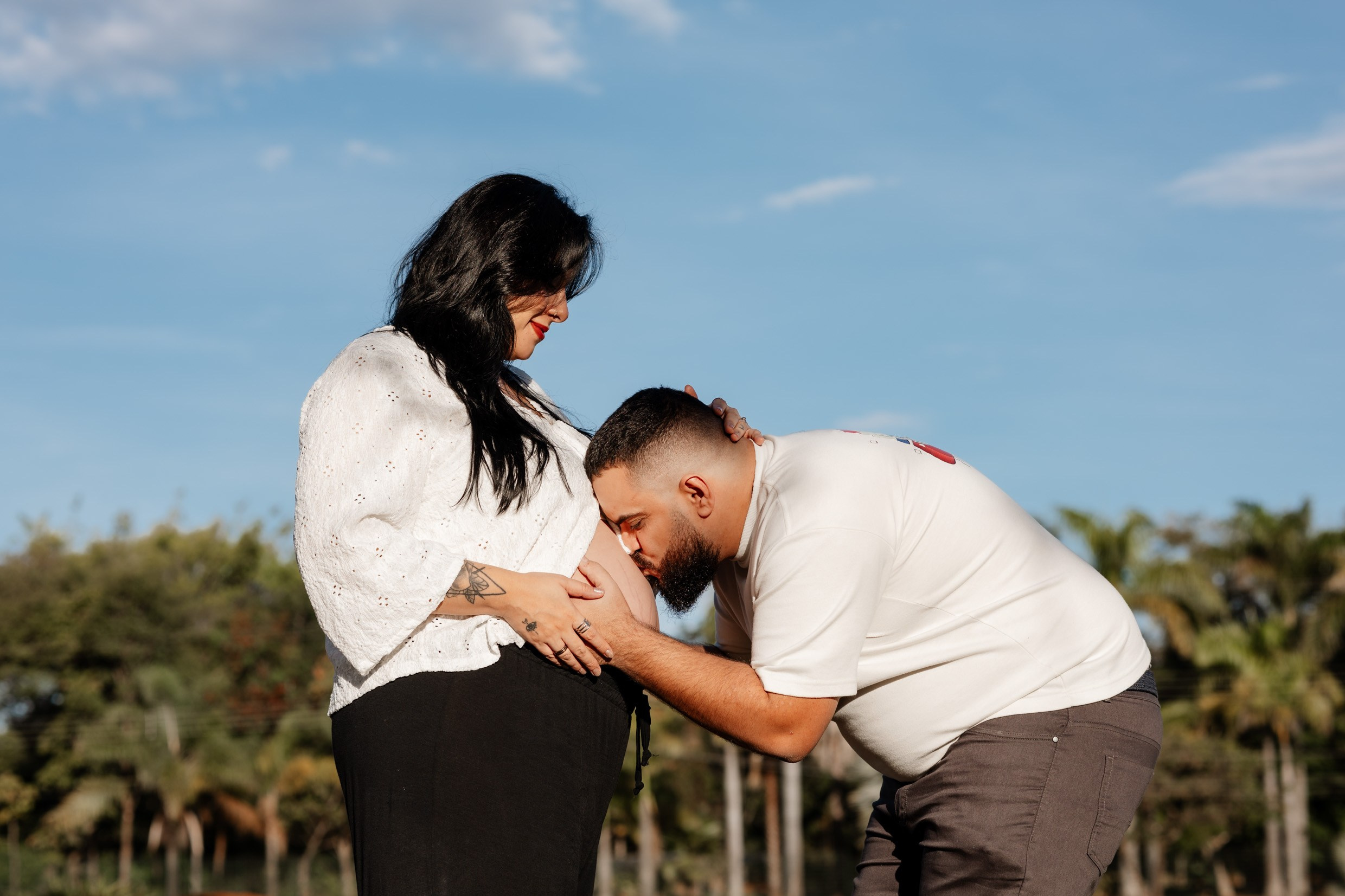 Pai beija a barriga da mãe no ensaio gestante.