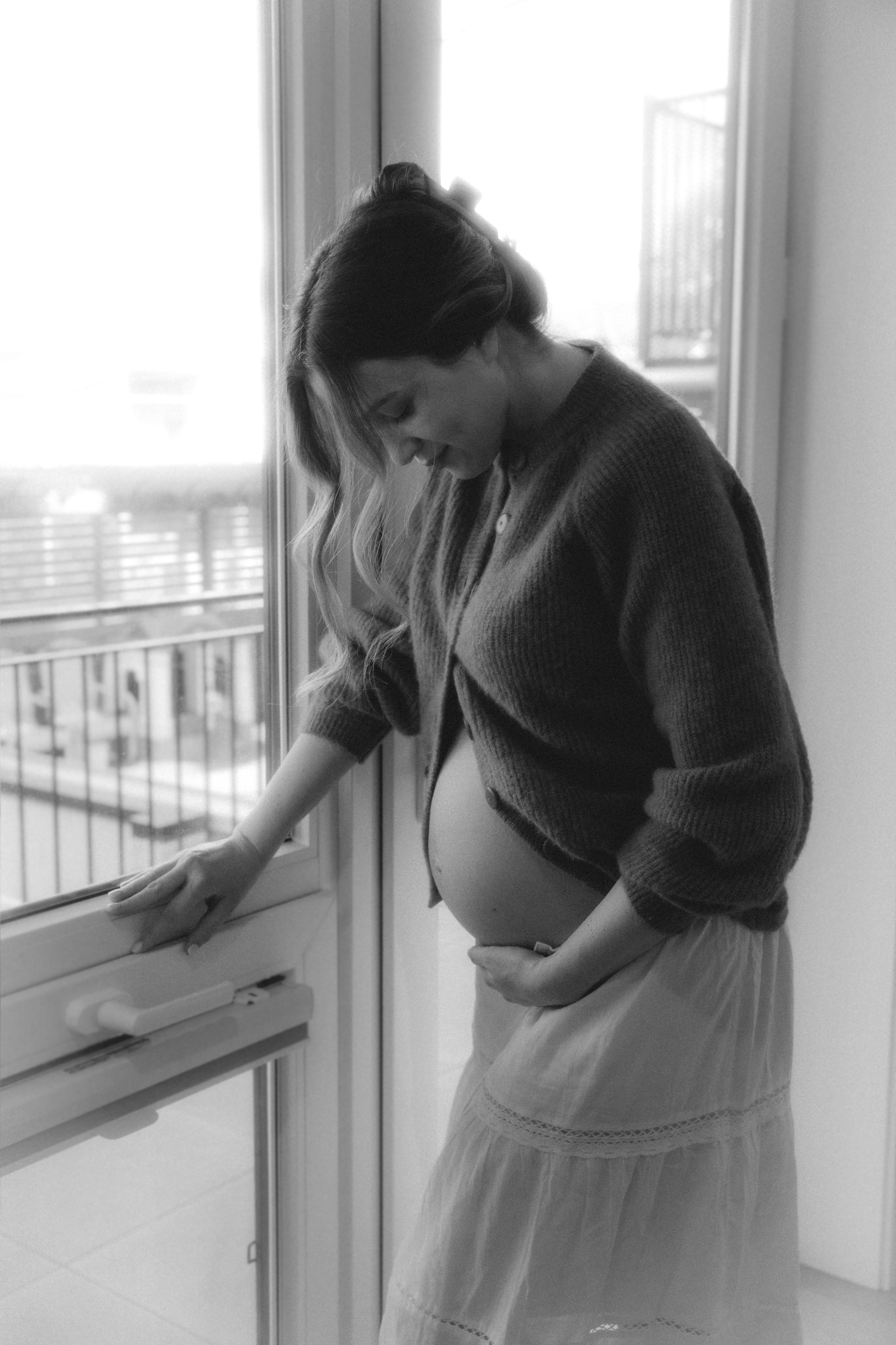 Expecting mom sitting in a calm studio space with natural light and florals