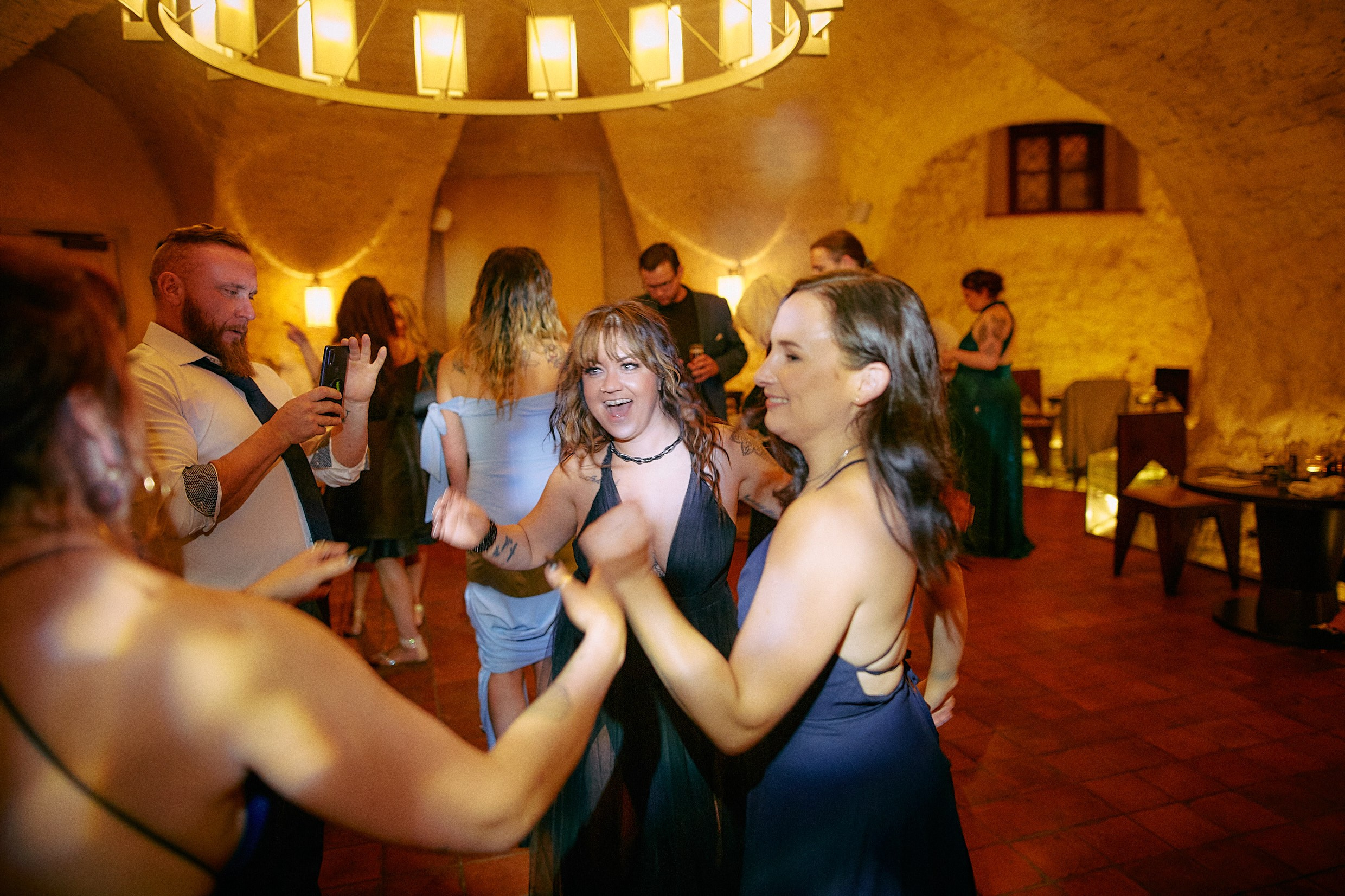 Group of guests dancing singing together at energetic wedding party.