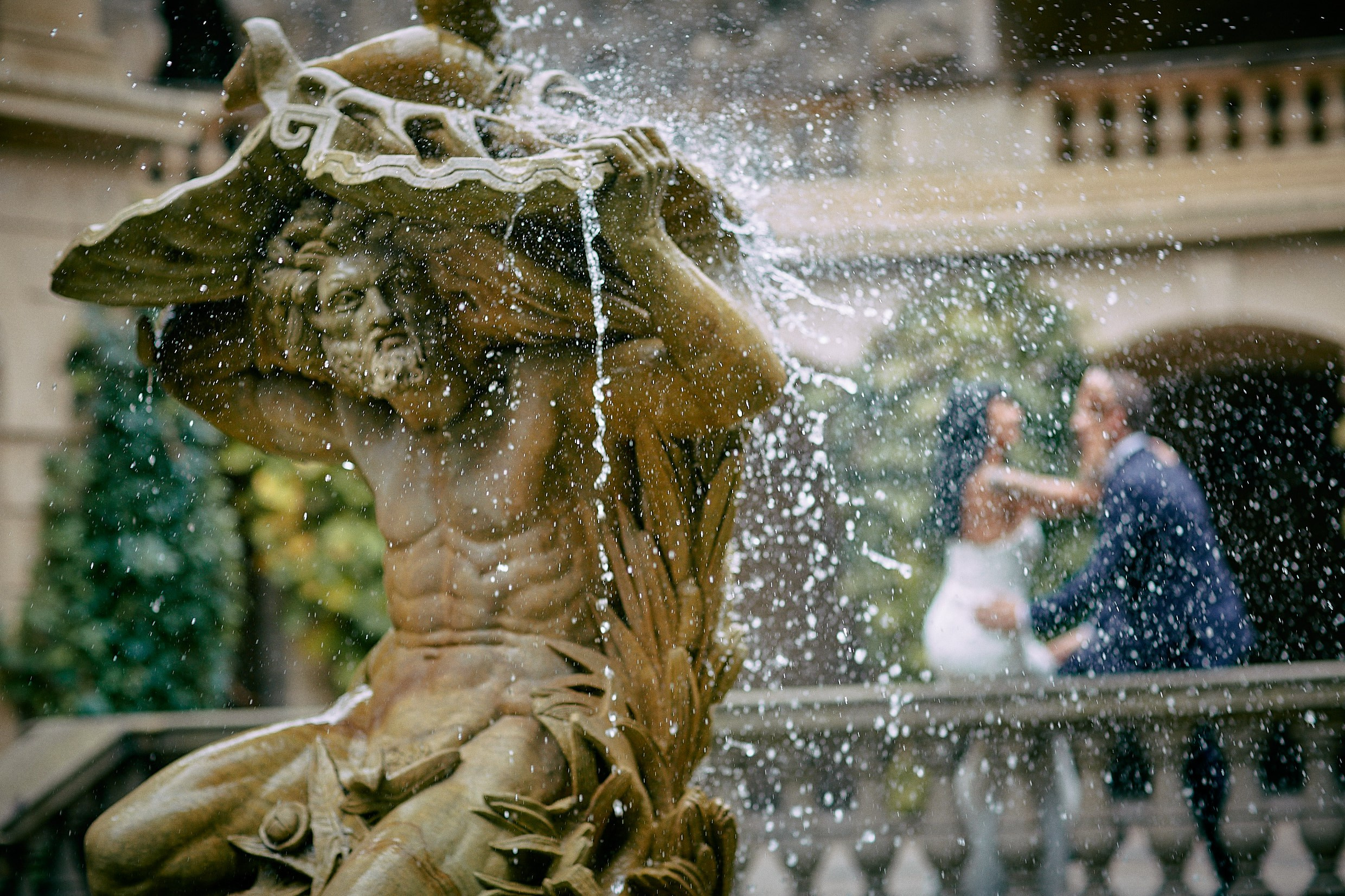 Couple kissing through water droplets Neptune fountain Grebovka Park.