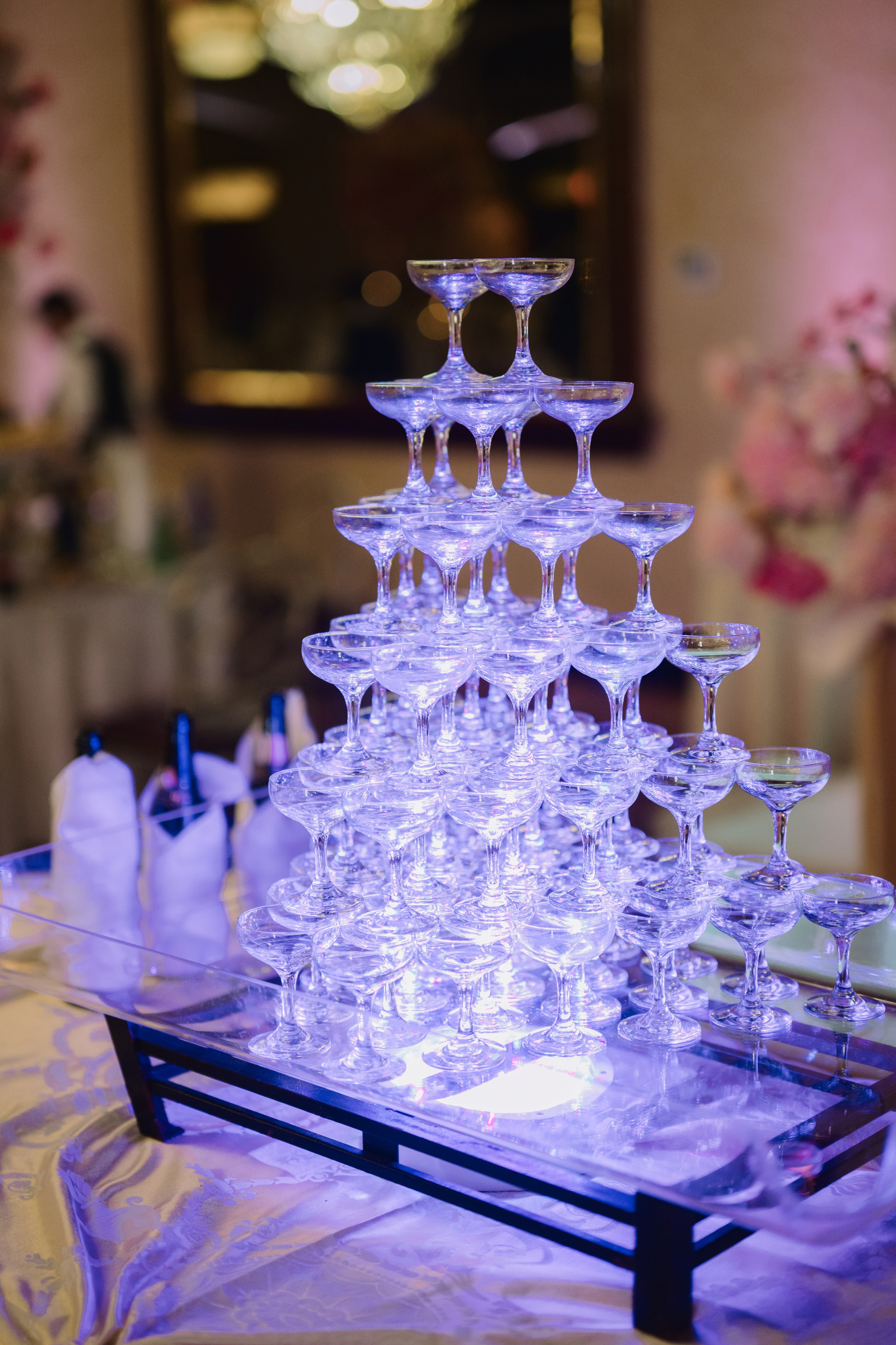 a table with a glass cake stand and wine glasses