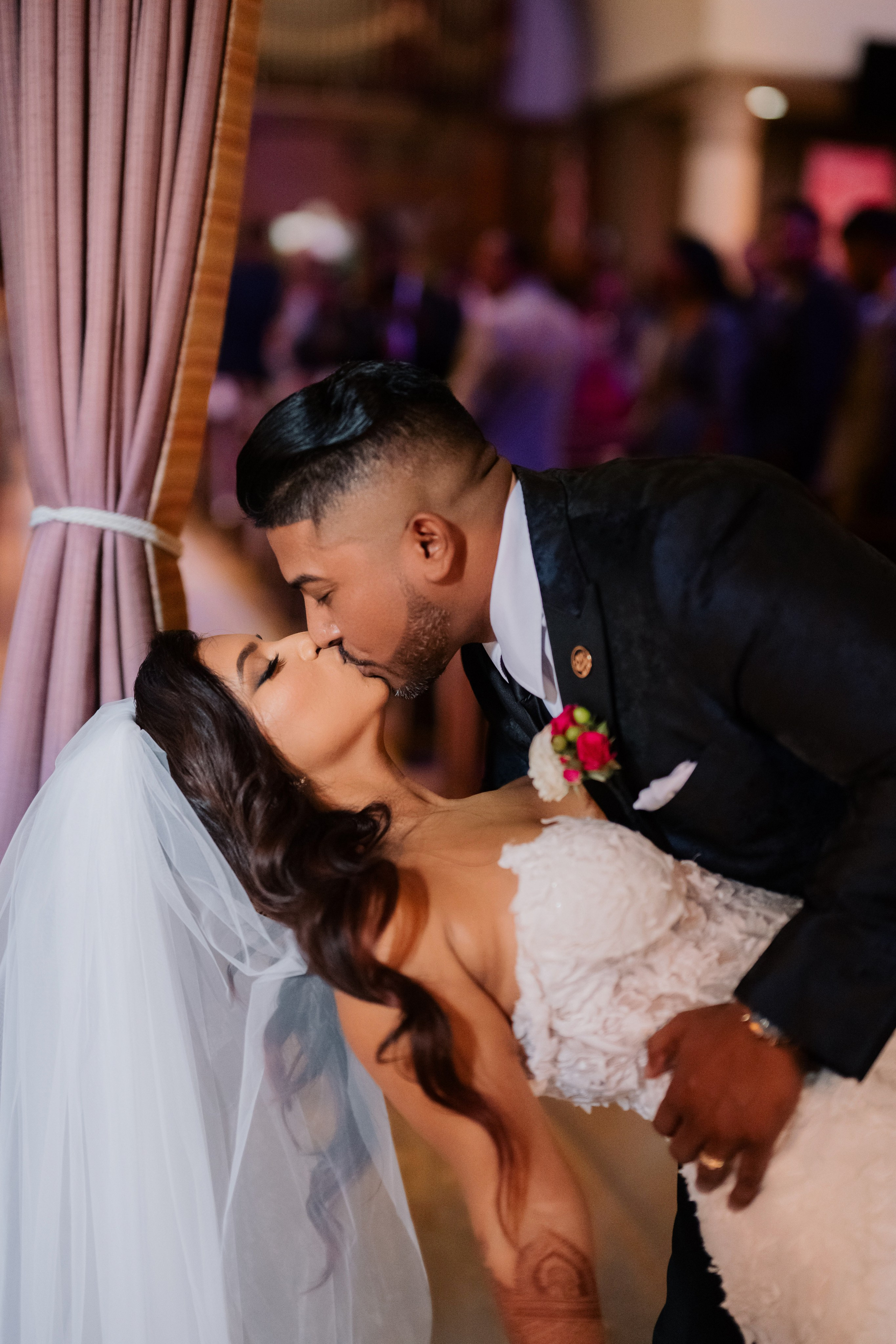 a bride and groom kissing in a room