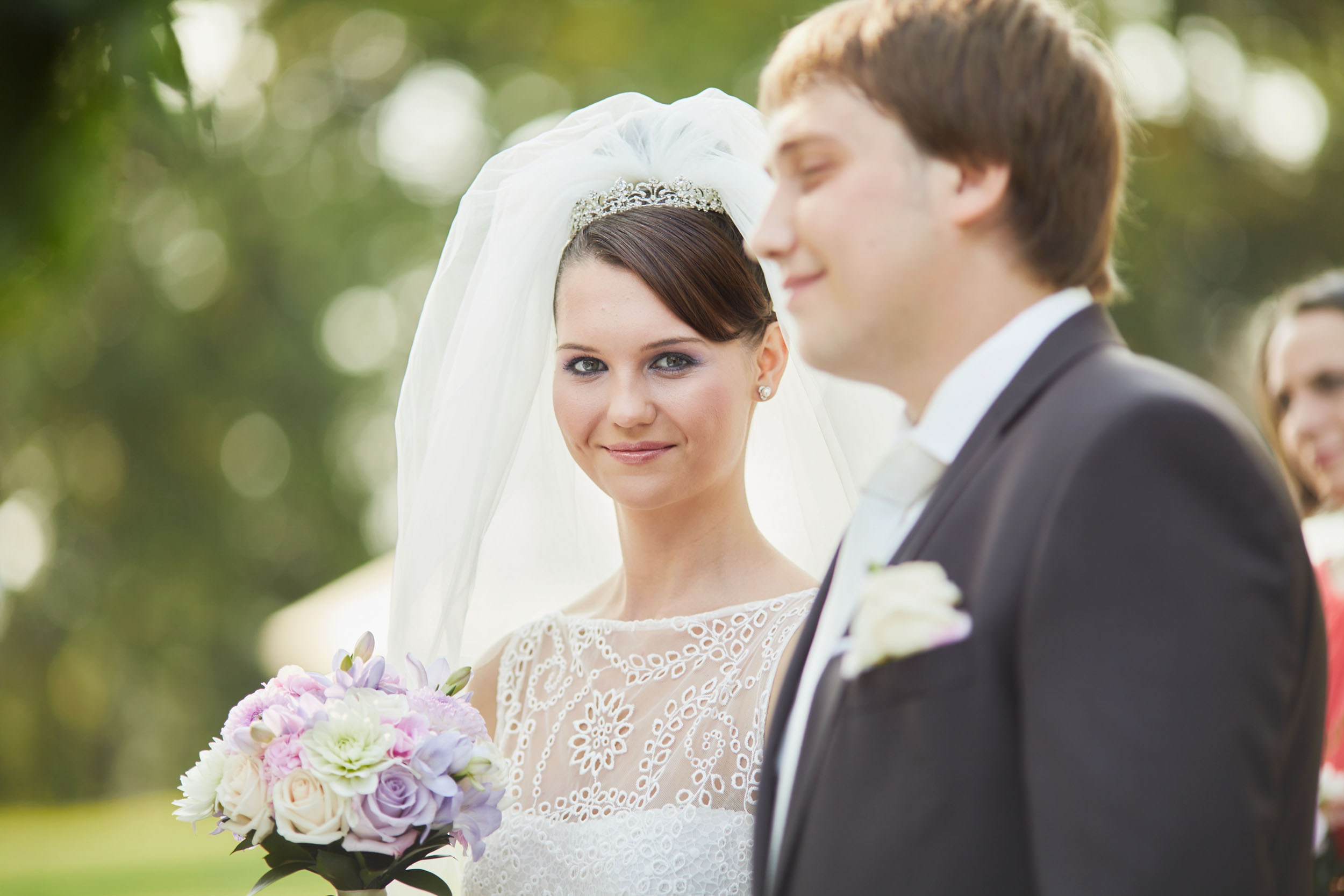 Ludmila smiling at camera during wedding ceremony at historic chateau.