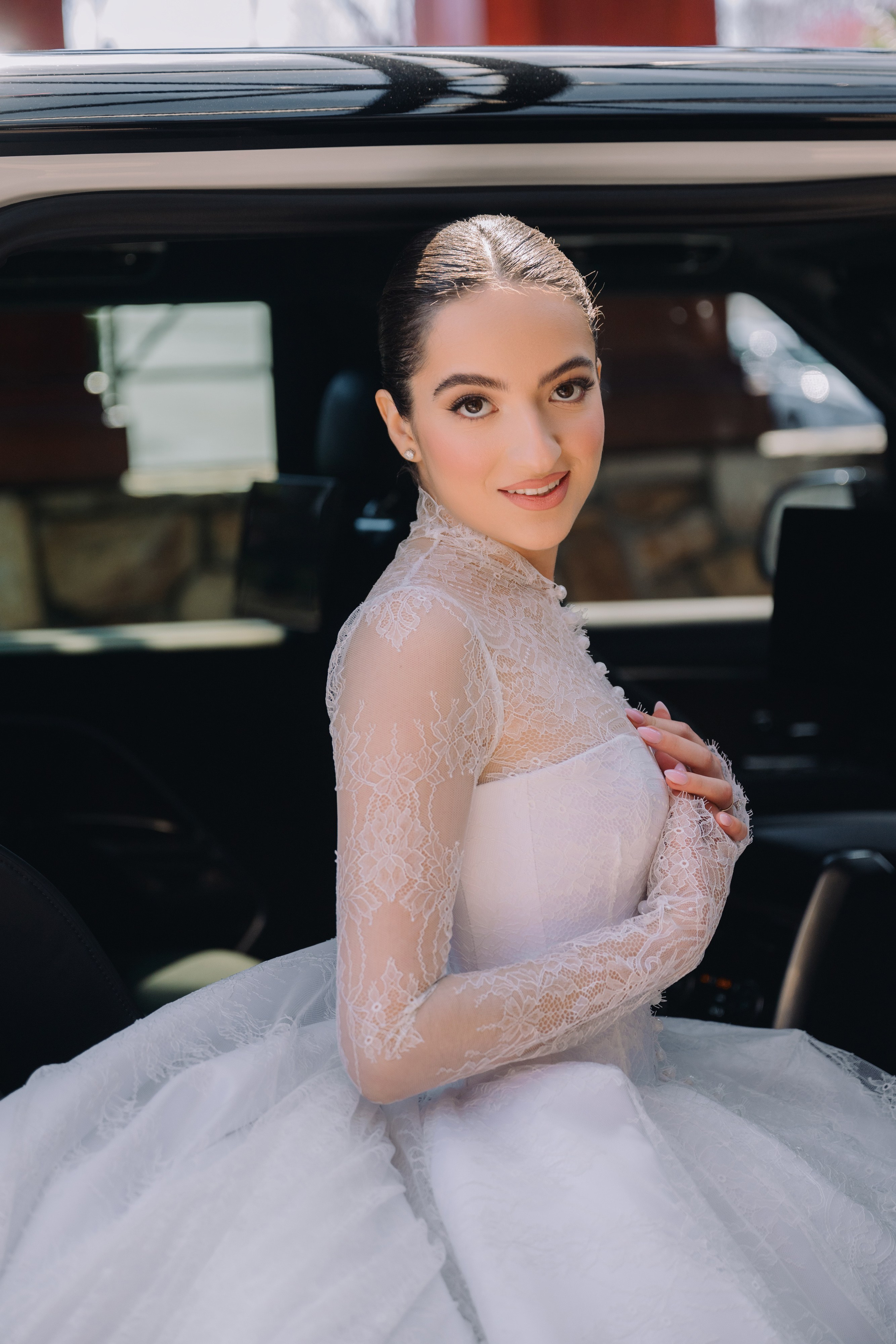 a woman in a white dress is sitting in the back of a car