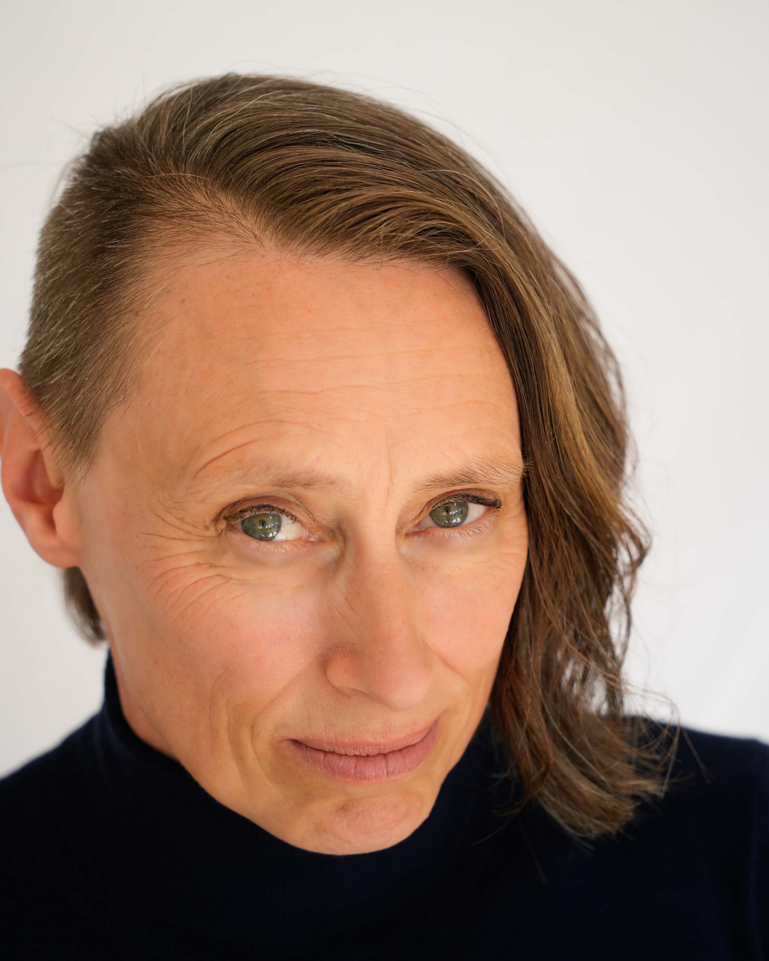 Moody headshot of female actor with expressive eyes and shadowed lighting, for theatrical and dramatic roles.
