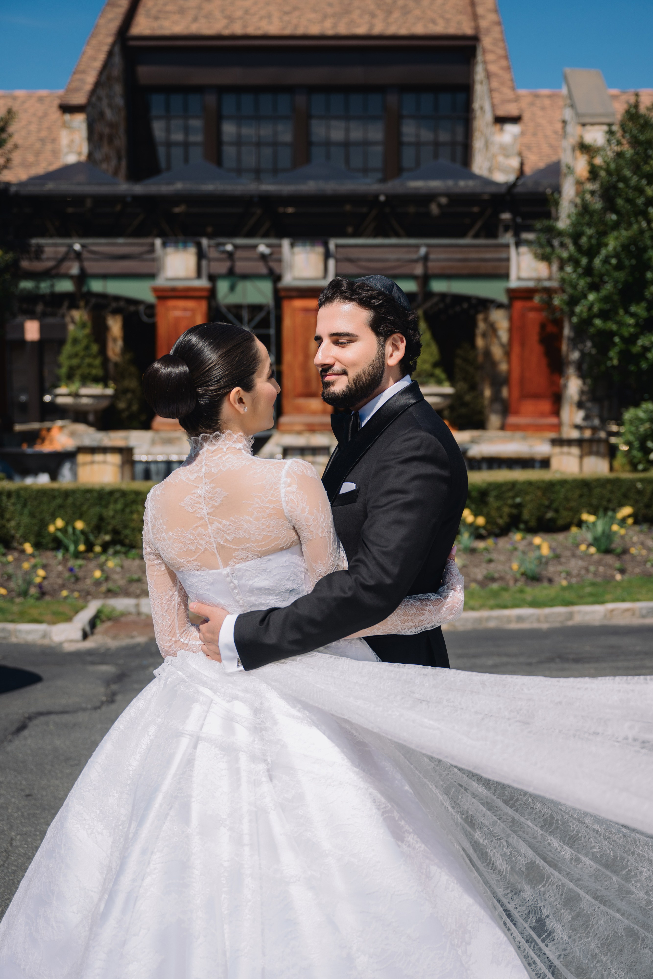 a bride and groom pose for a photo in front of a house
