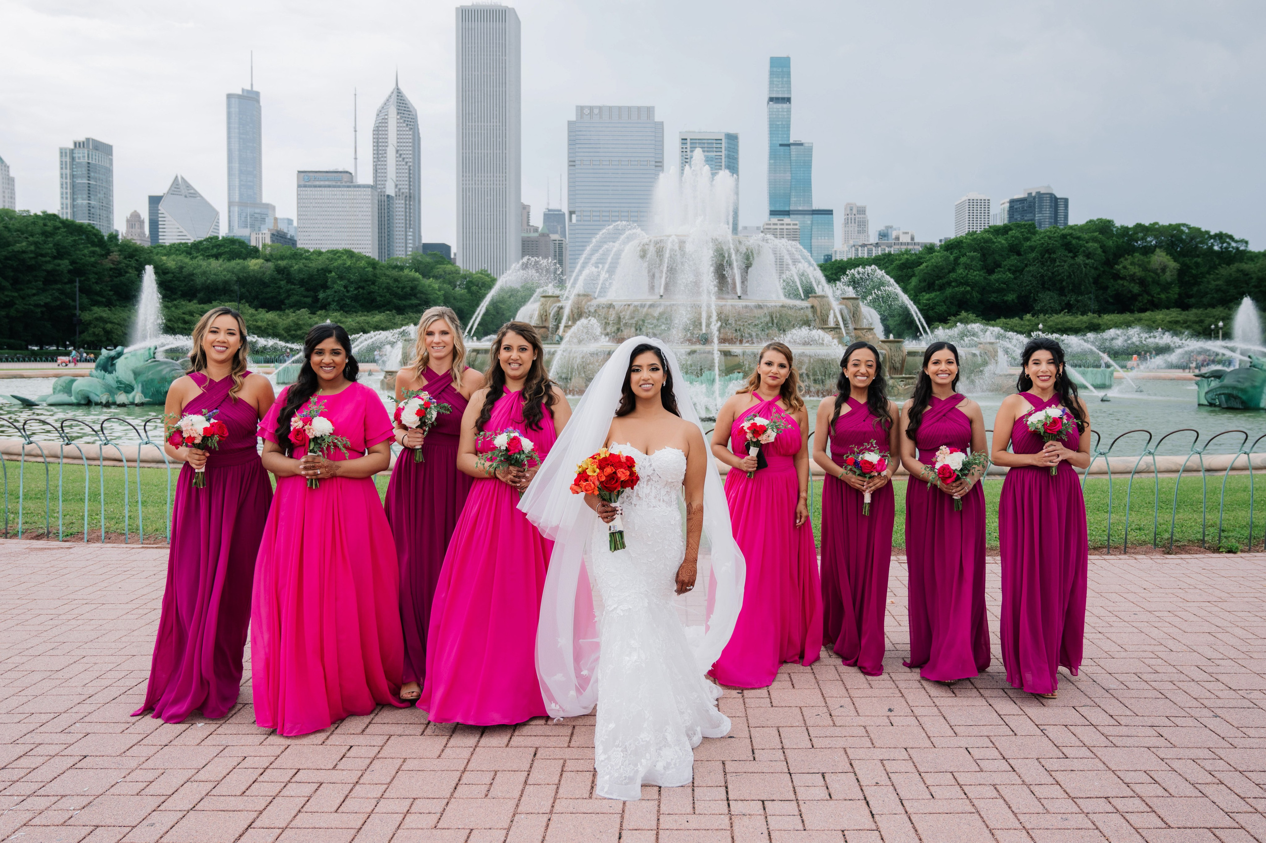 a bride and her bridesmas pose in front of the buckingham gardens